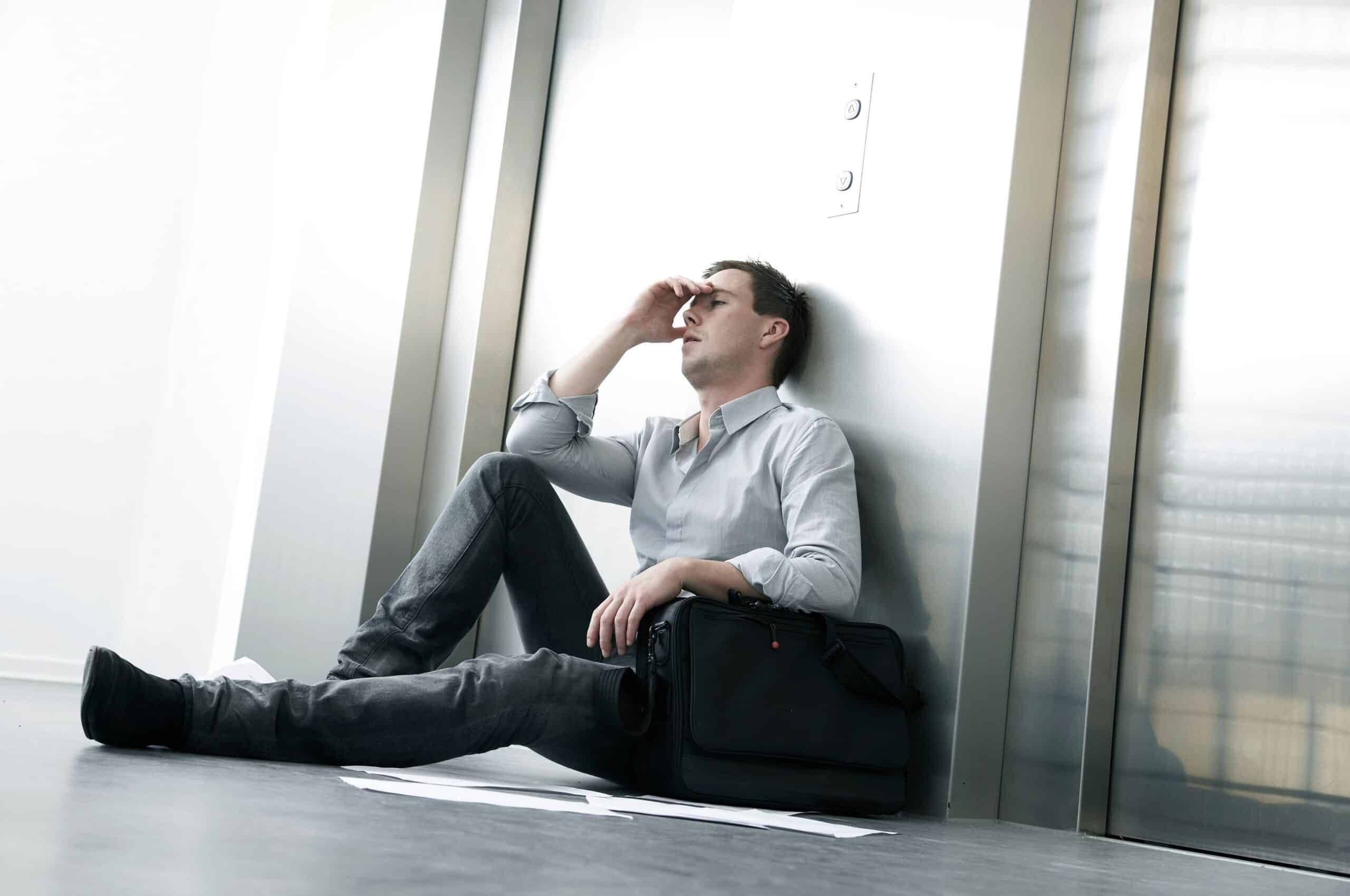 Trakassering: Fortivlet mann sitter på gulvet utenfor en heis.