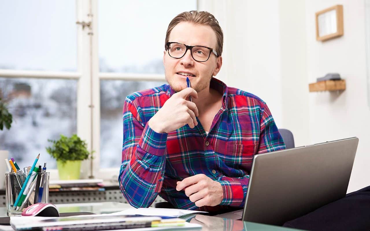 Motivasjon: Mann med briller sitter og tenker ved skrivebordet.