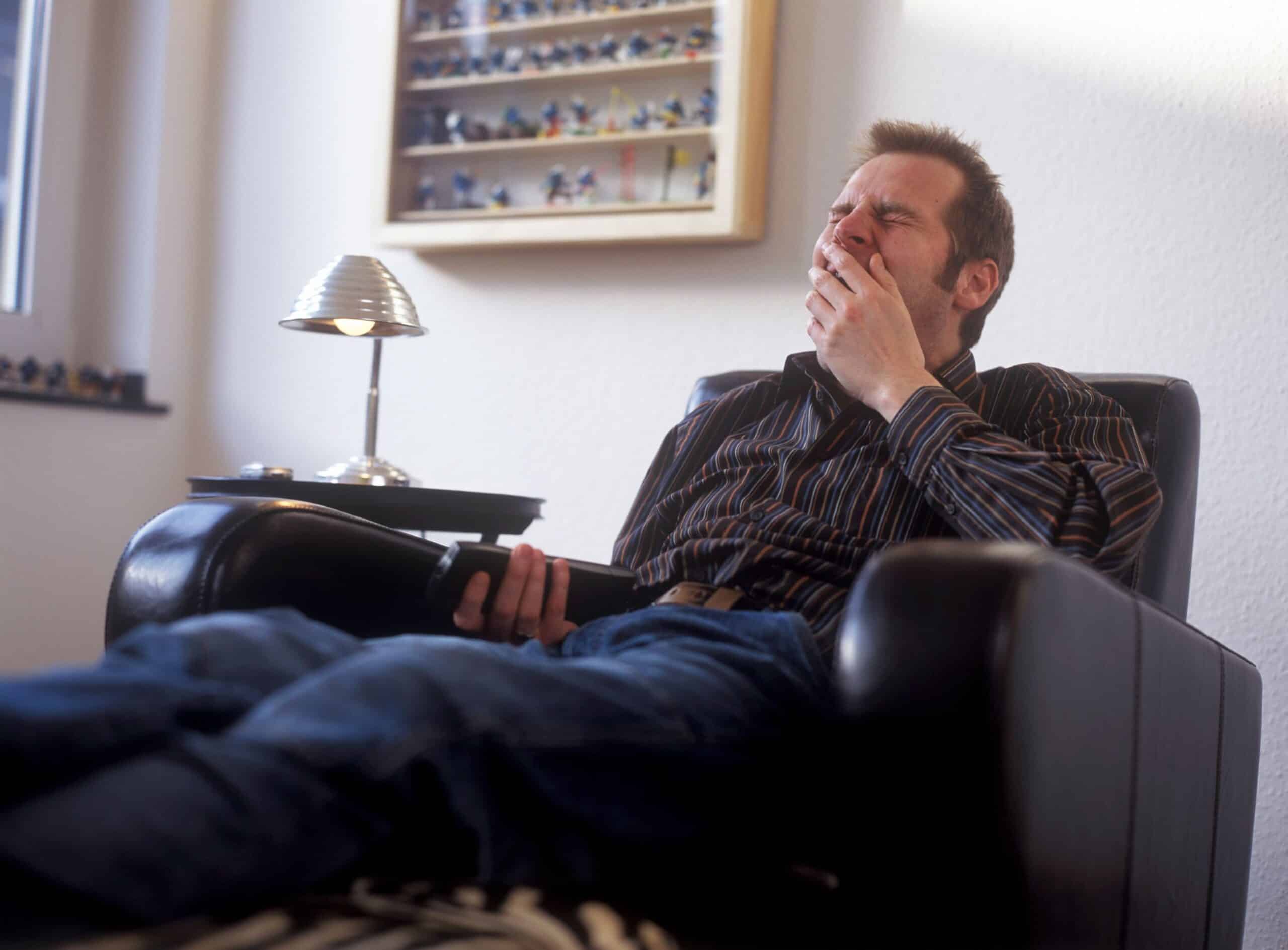 Kommunikasjon: Mann sitter i en skinnstol og gjesper.