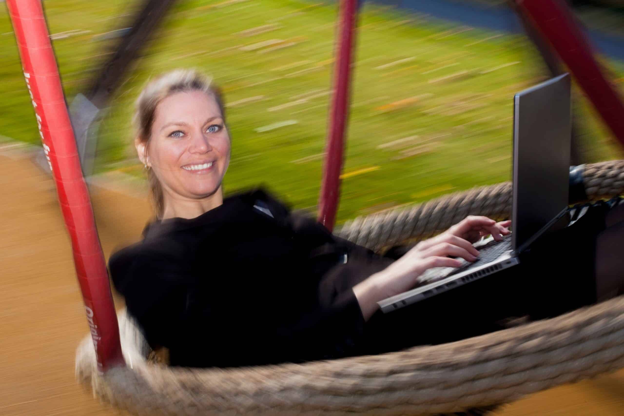 Lønnsomhet: En kvinne sitter i en stor huske med en laptop på fanget.