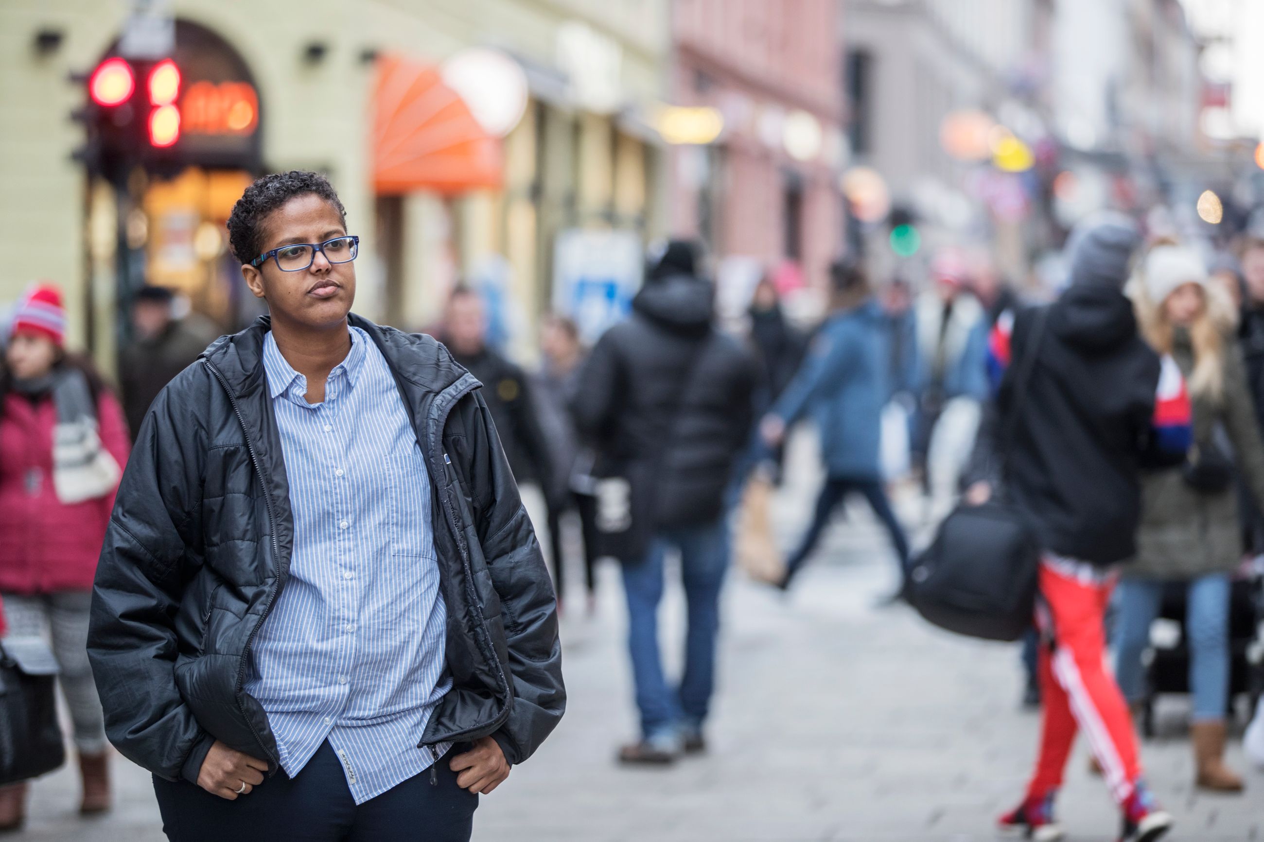 Likestilling: Mørk kvinne i blå jakke står i menneskemylderet i en oslogate.