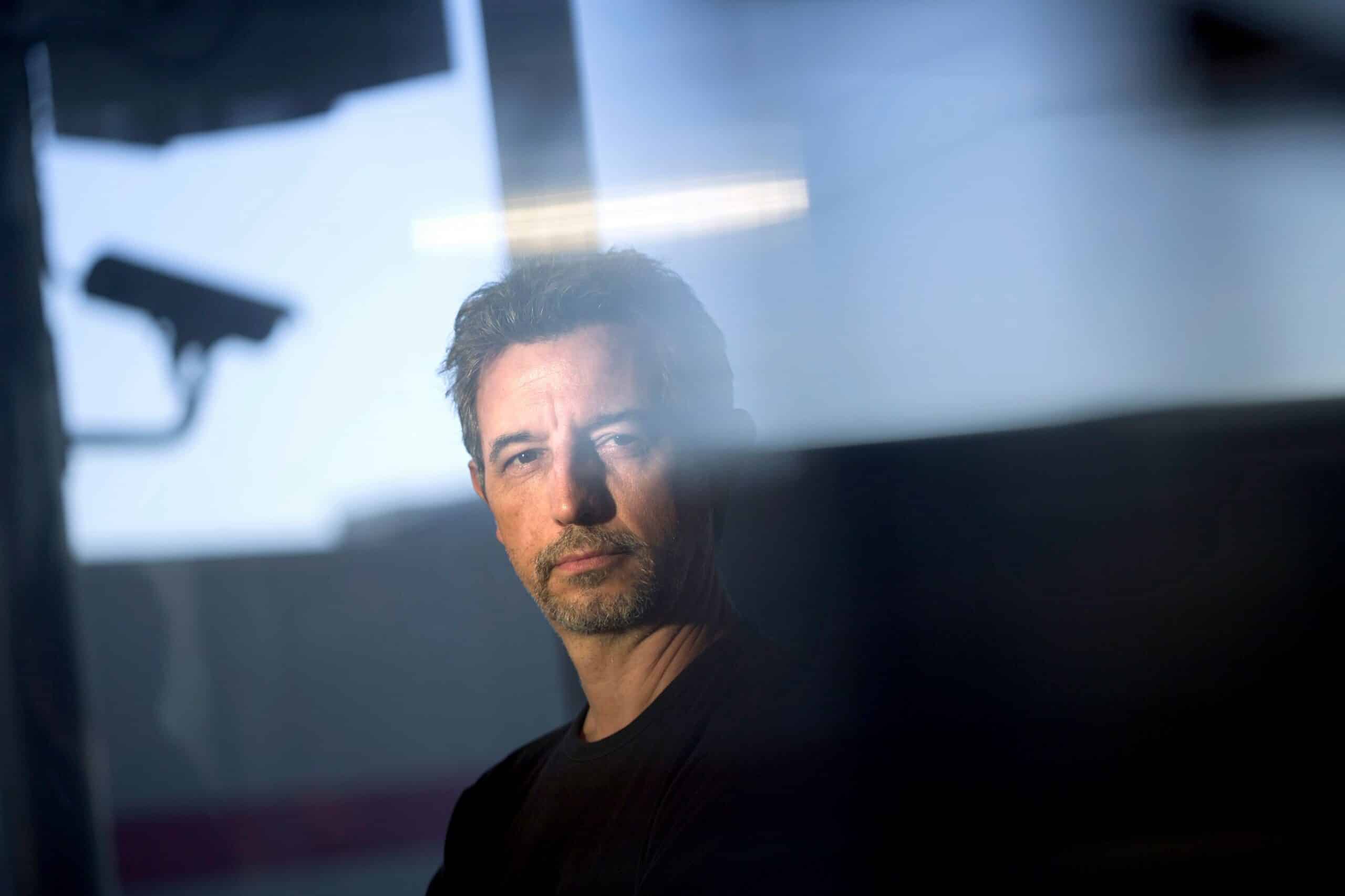 Kontroll: Mann står i halvmørket med et overvåkningskamera i bakgrunnen.