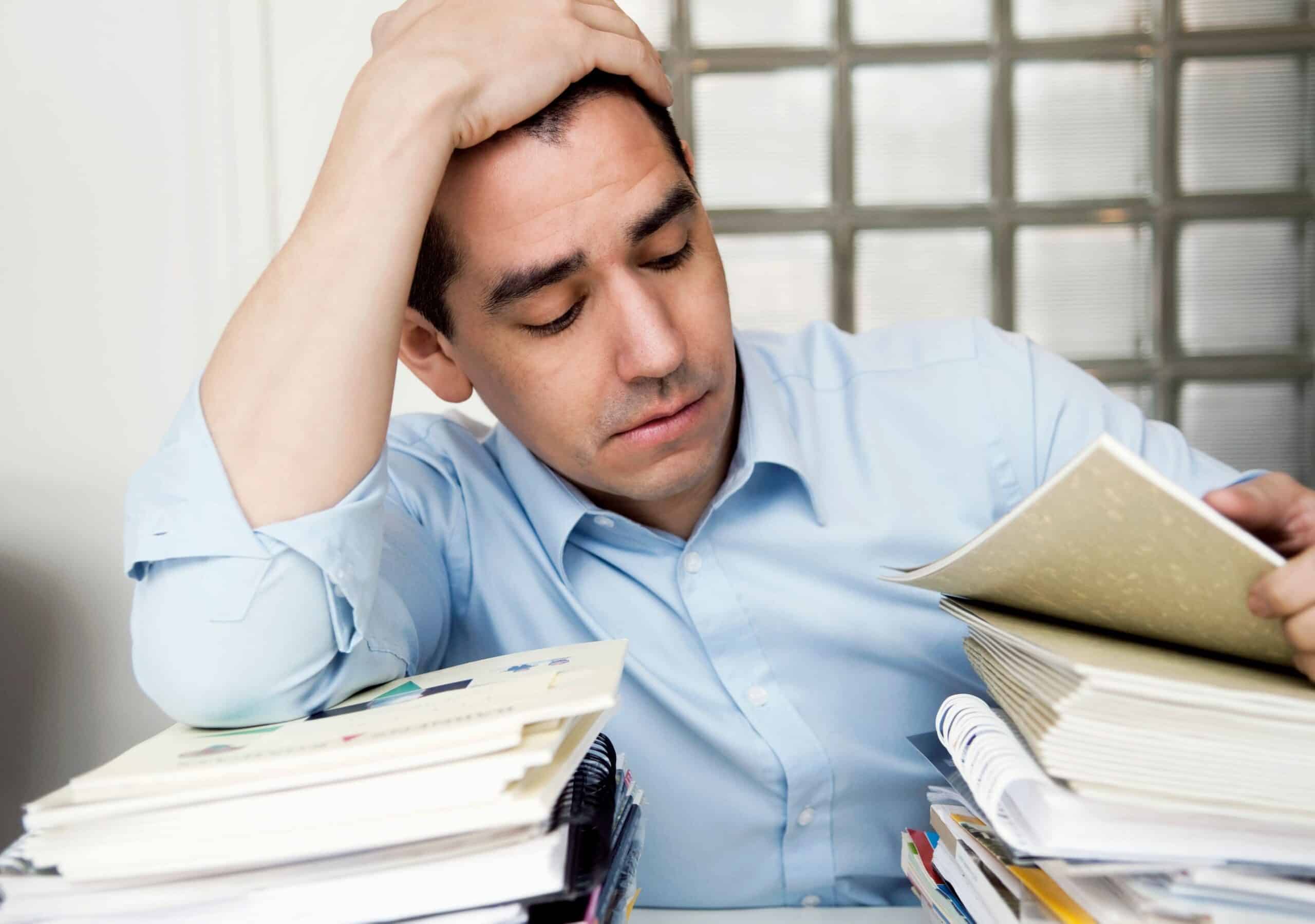 Følelser: Fortvilet mann sitter med to store bunker foran seg på skrivebordet.