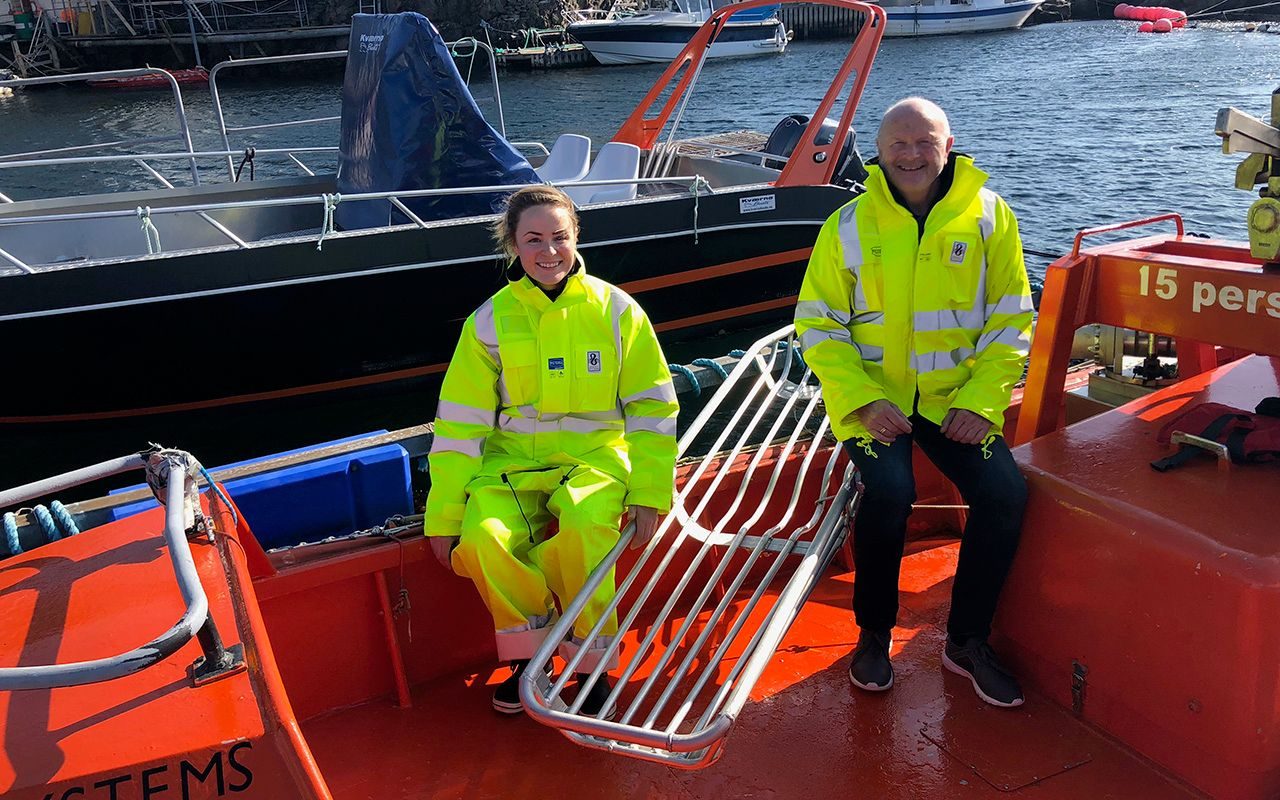 Innovasjon: Ung kvinne og eldre mann sitter i en båt og viser fram en redningskurv.