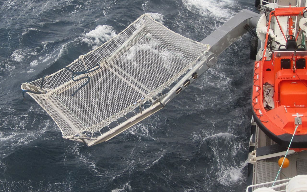 Innovasjon: En stor kurv i metall ligger over sjøen. På høyre side ses siden av en båt.