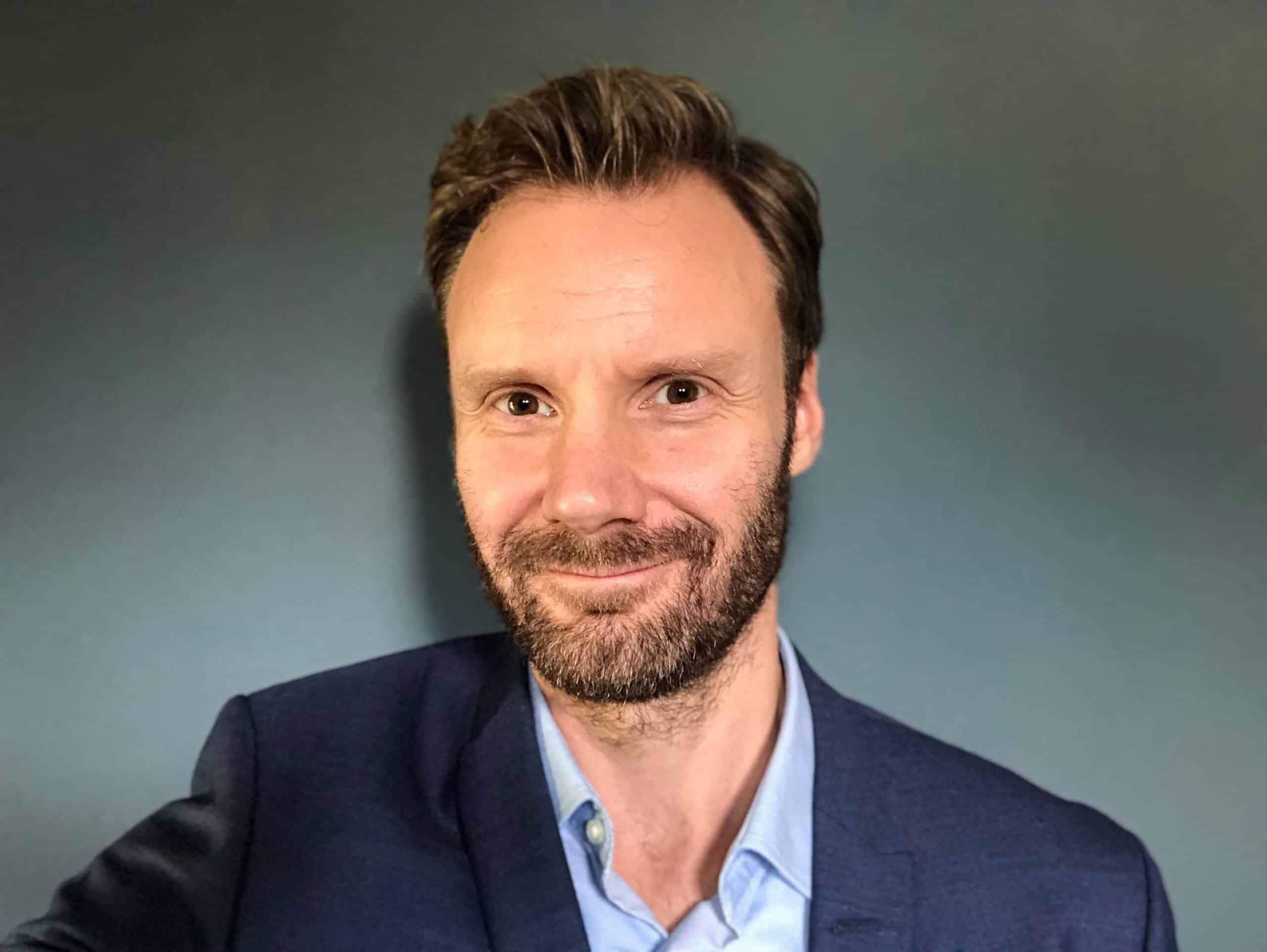 Leder: Mann med skjegg ser rett i kameraet.