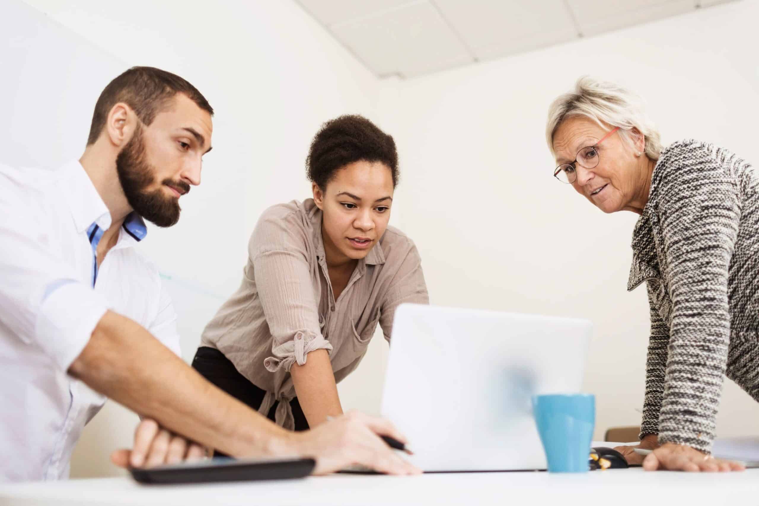 Læring: To kvinner og en mann jobber sammen over en laptop.