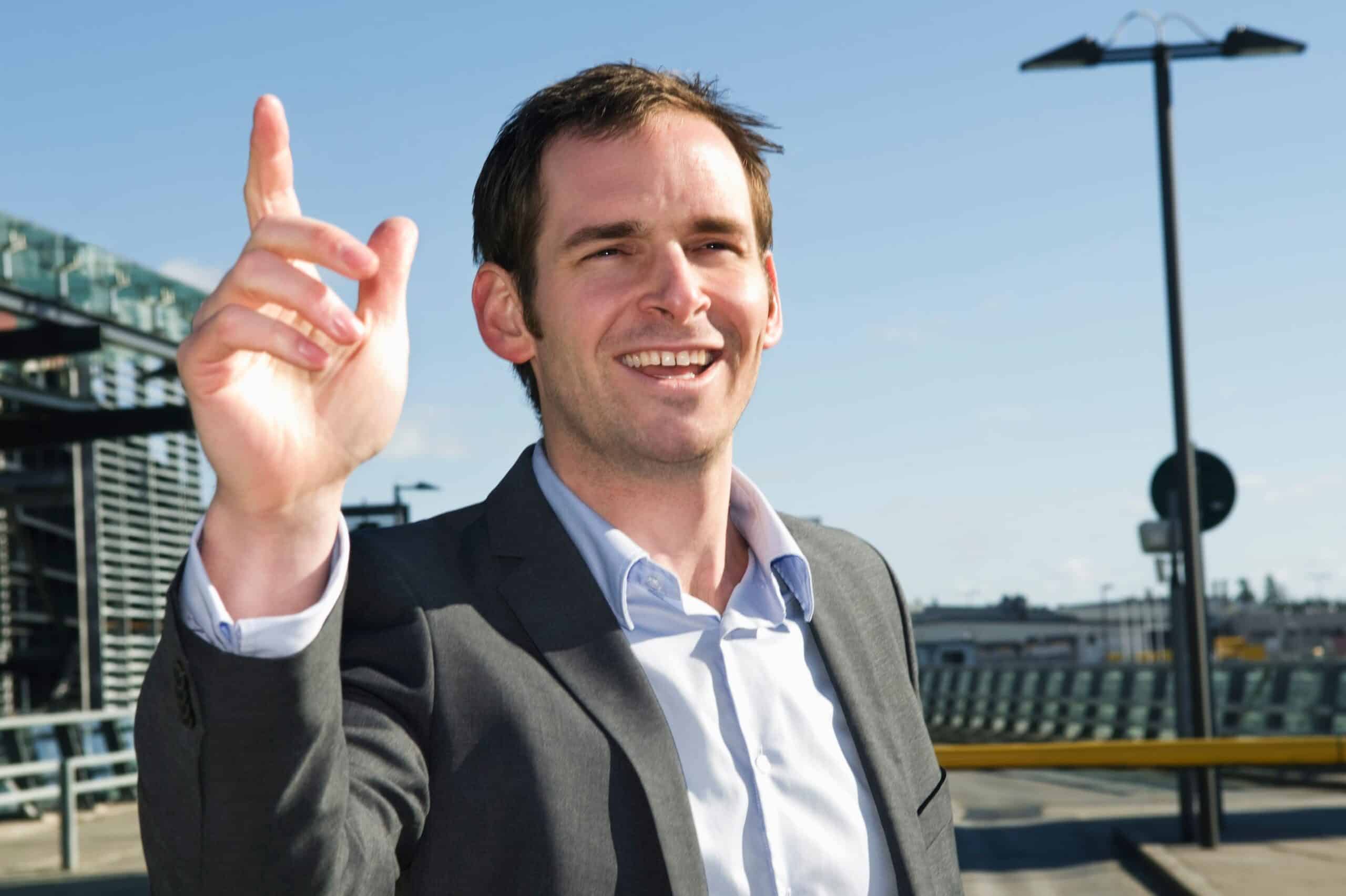 Suksess: Blid mann står utenfor en flyplass med hevet pekefinger.