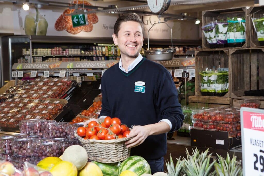 Digitalisering: Blid mann står i frukt og grønt-disken i en matbutikk.