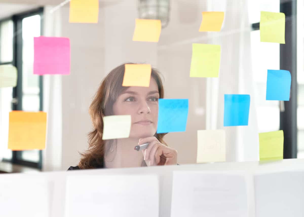 Stress: Kvinne står bak en glassvegg med mange notatlapper.