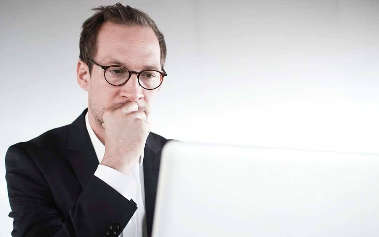 Usikkerhet: Mann sitter foran en PC og ser usikker ut.