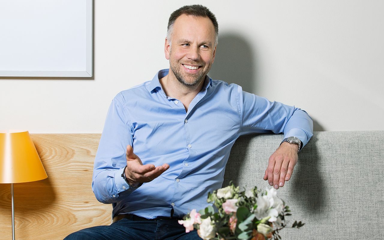 Krise: En smilende mann i sitter i en sofa og prater.