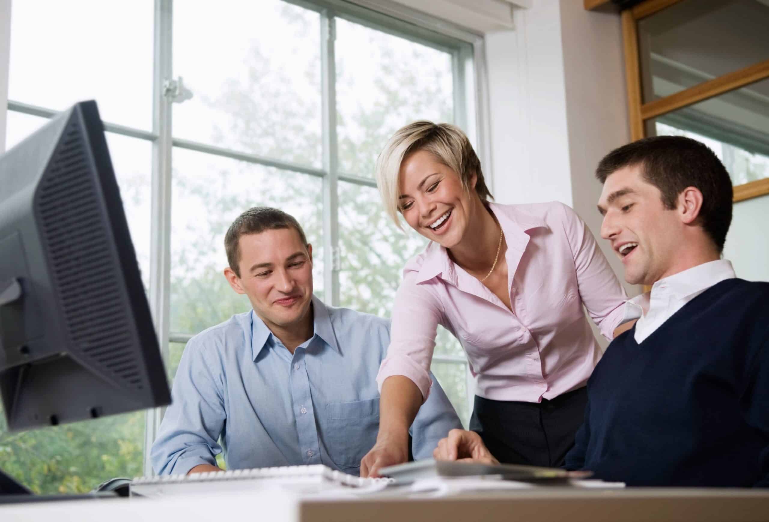 Rekruttering: Tre blide kolleger foran en PC-skjerm.