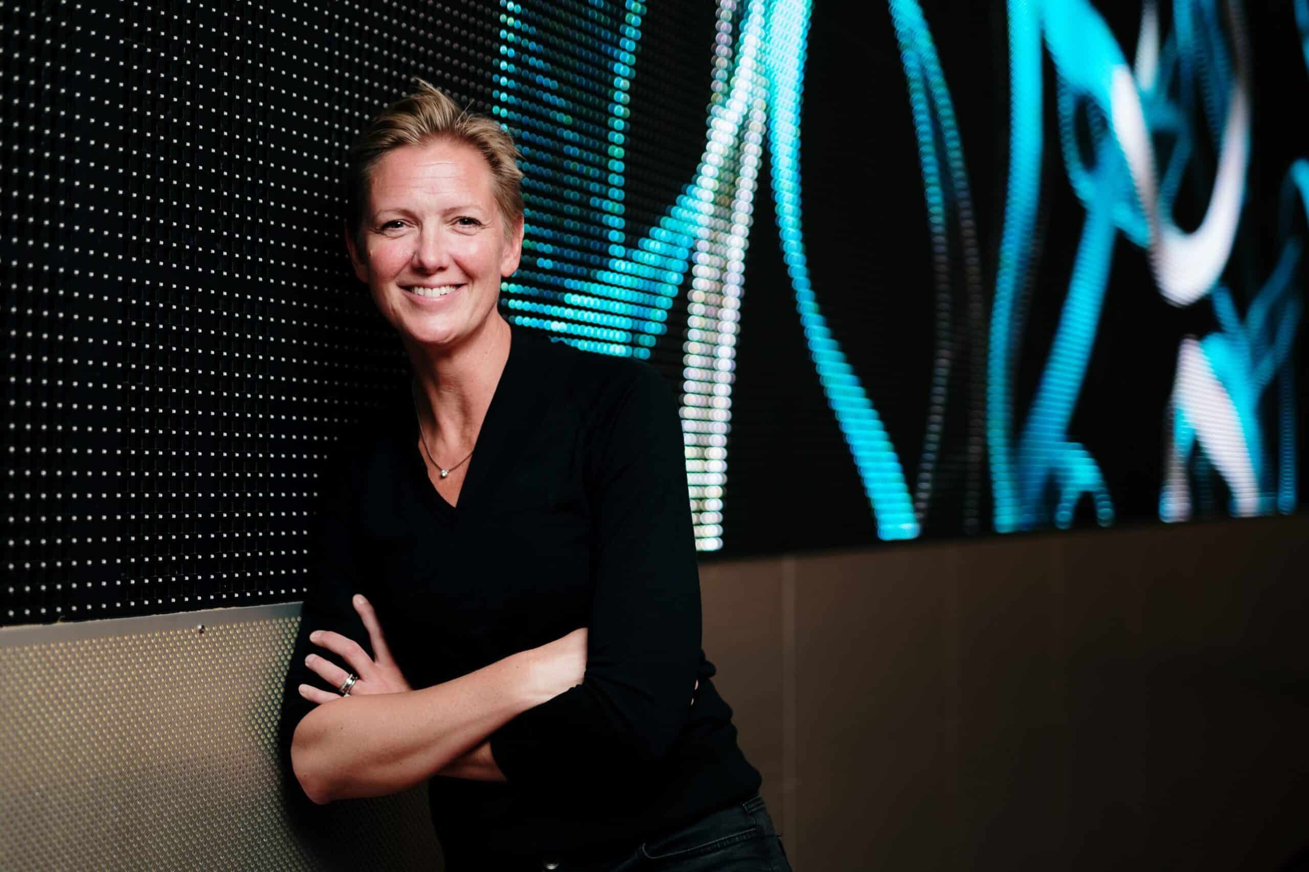 Teknologi: Blid kvinne står foran digital skjerm.