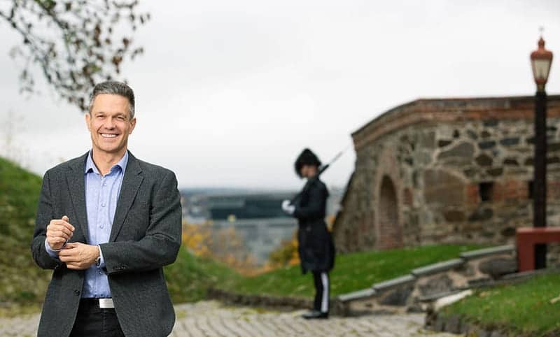 Forsvaret: Smilende mann står ute på Akershus Festning med en gardist i bakgrunnen.