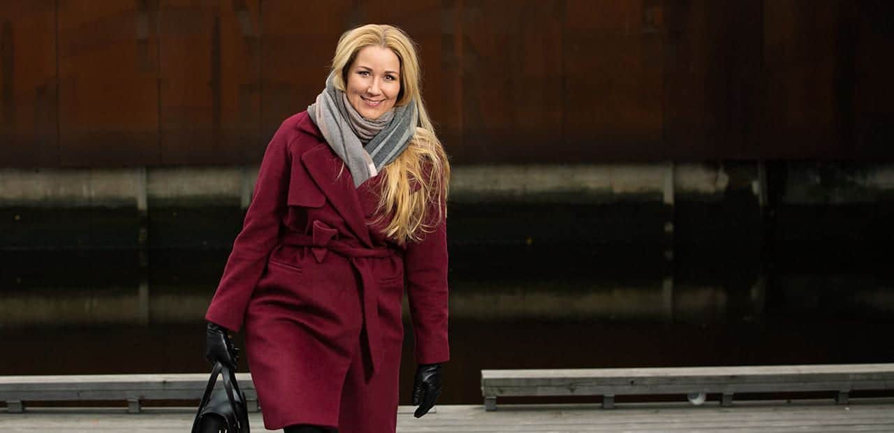 Konflikter: Blind kvinne med burgunerrød kåpe går opp en trapp utendørs.