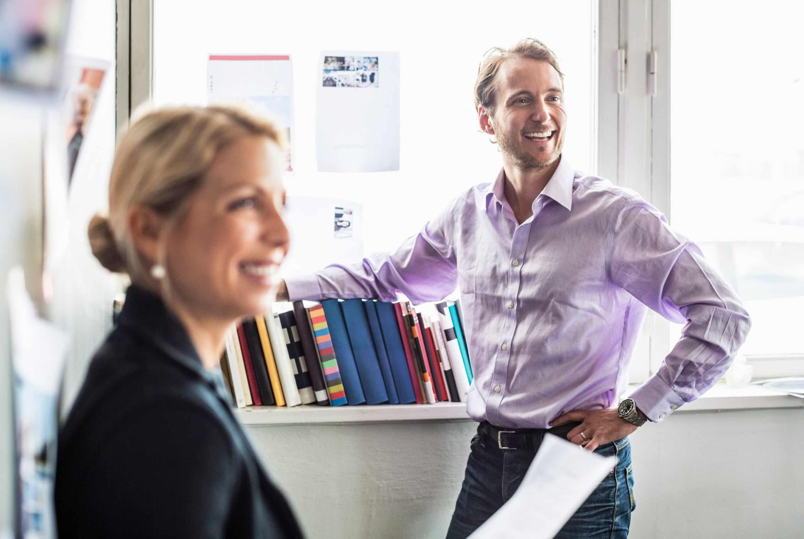 Smart: En mann og en kvinne står smilende i et kontor.