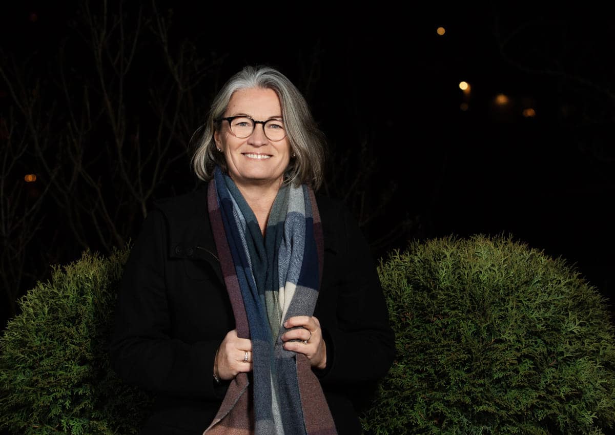 Mindfulness: Blid dame står utendørs med et skjerf rundt halsen.