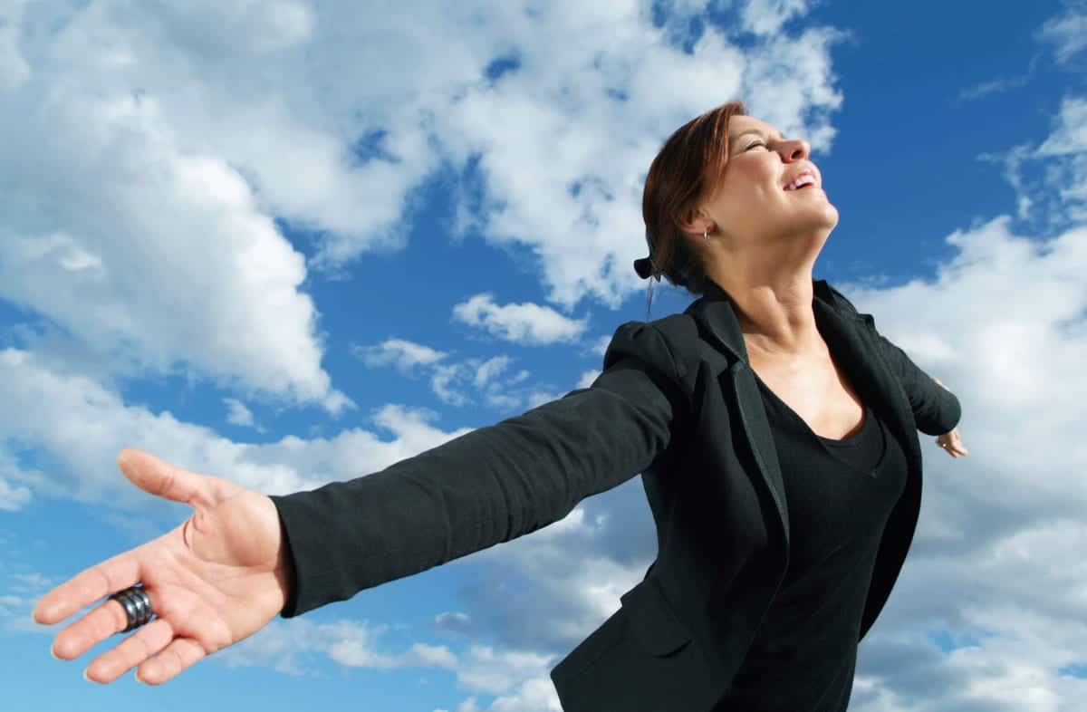 Mellomleder: En kvinne med lukkede øyne lener seg framover, og i bakgrunnen ses blå himmel med skyer.