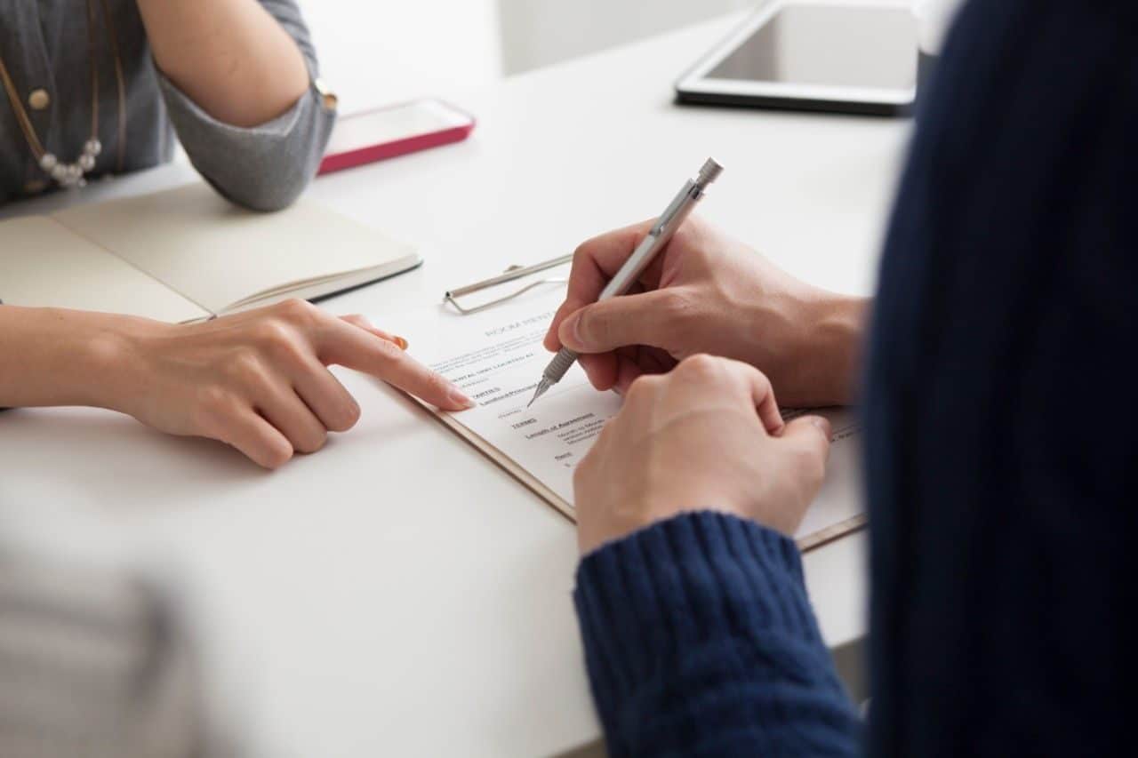 Hendene til to personer som signerer et dokument. Illustrasjon til sak om saksbehandlingsregler og varsling