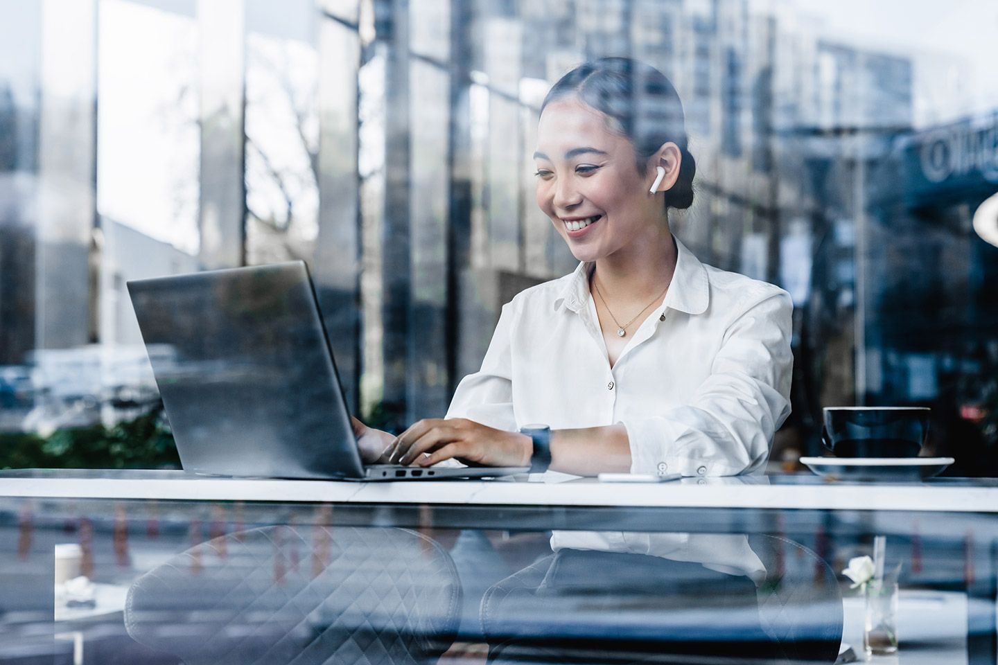 Kvinne som sitter med pc fotografert utenfor et vindu