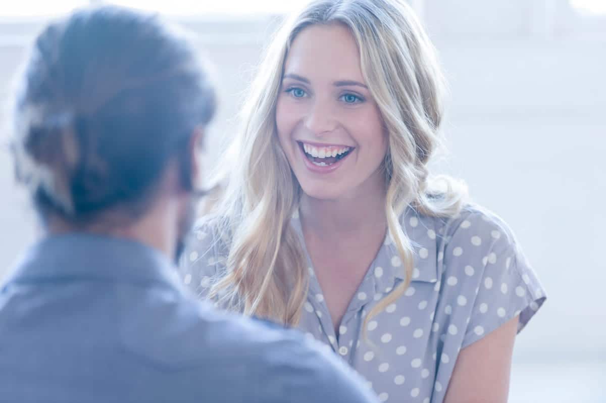 Kvinne med blondt hår smiler til mannlig kollega. Illustrasjon til sak om å lykkes med HR for Lederne