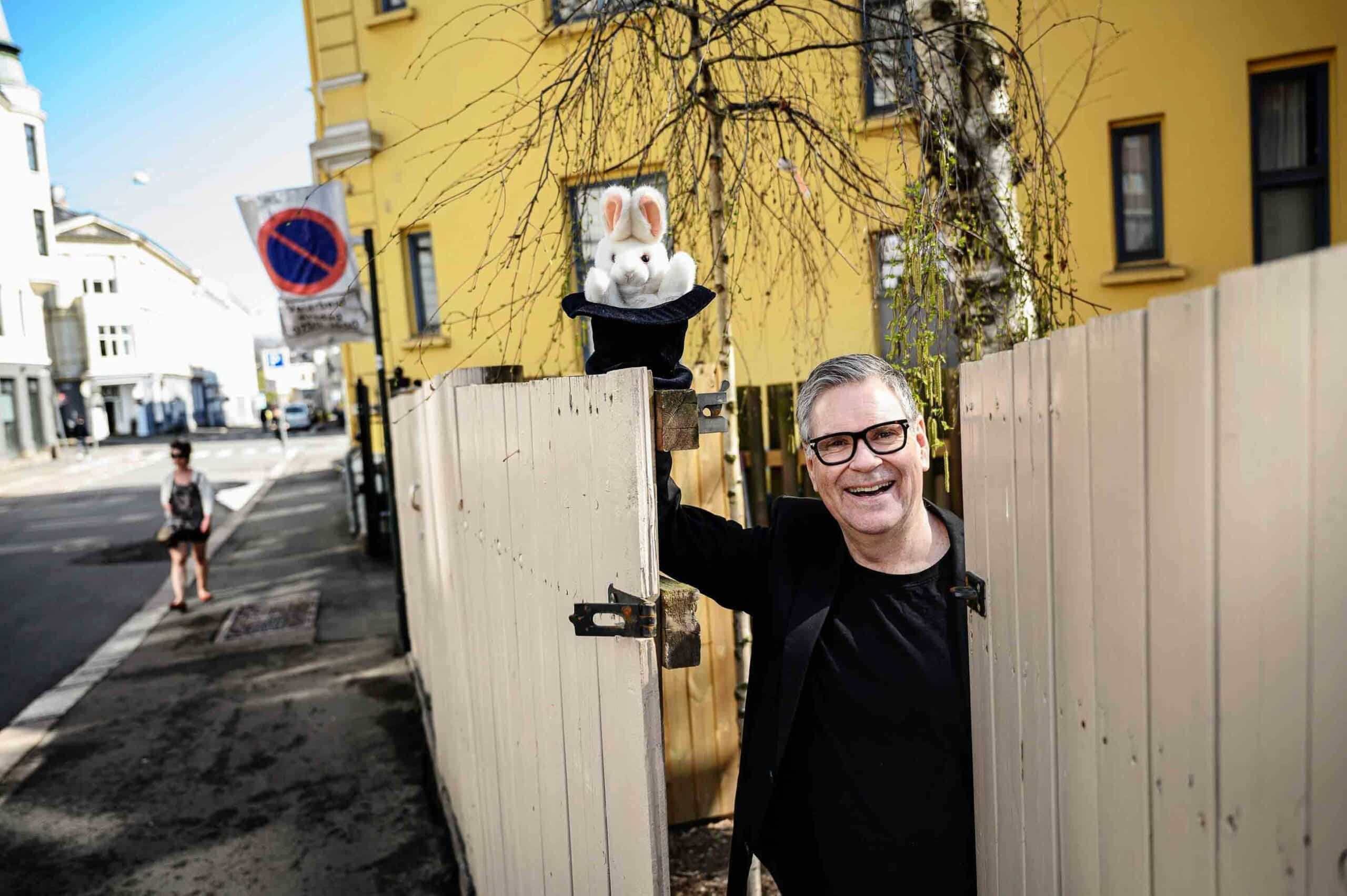Jon Morten Melhus, mann som står i en åpemn port og holder en lekekanin i en sort hatt