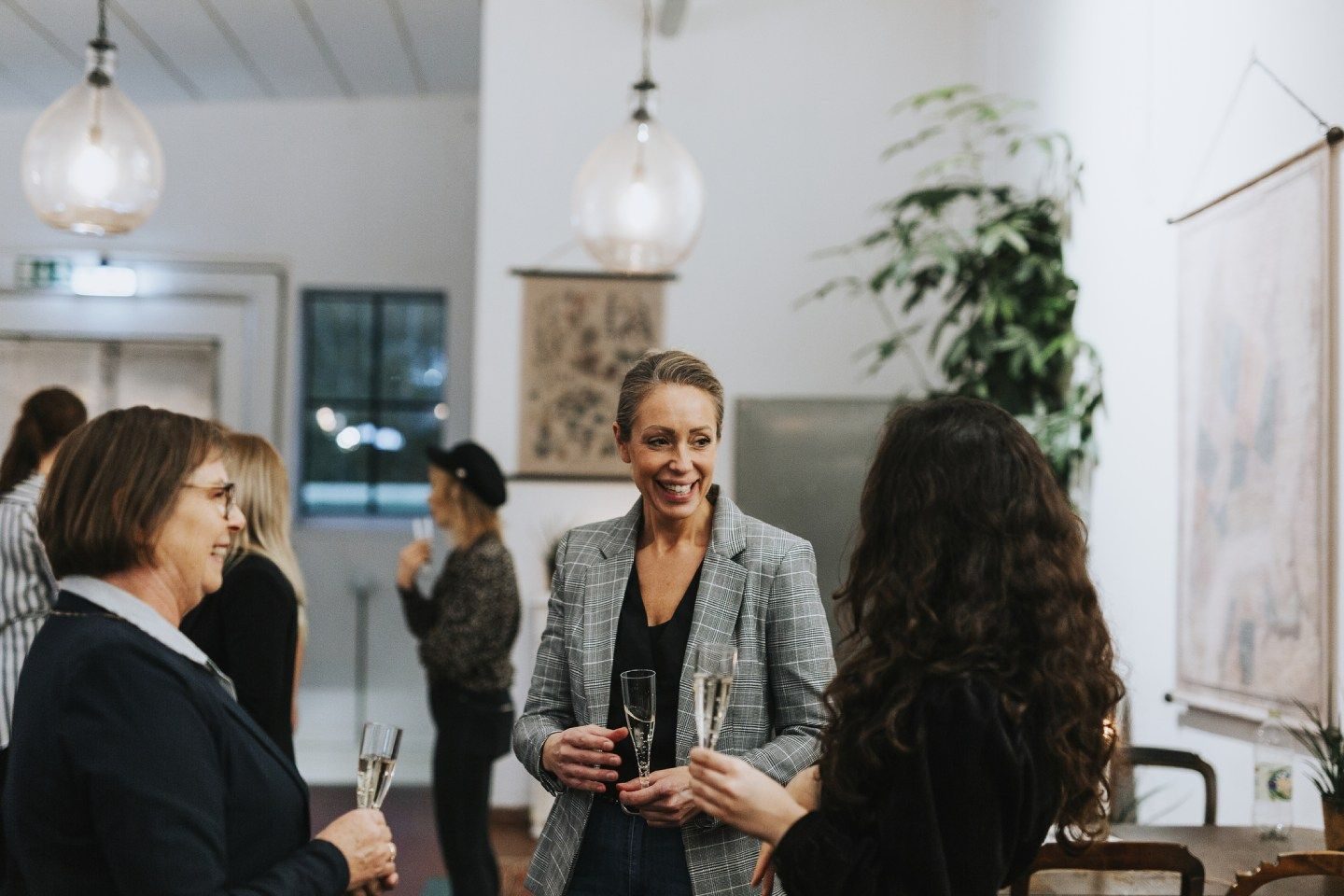 Tre kvinner som snakker og ler sammen på sosialt jobbarrangement 