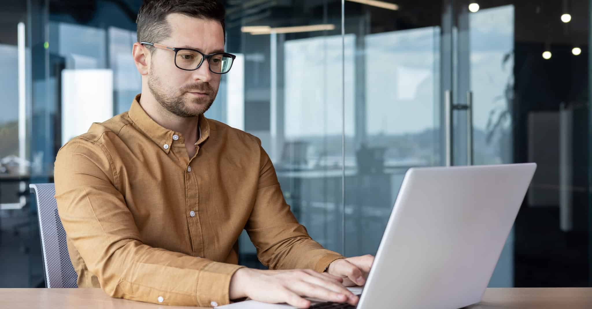 Mann sitter konsentrert ved en pc.