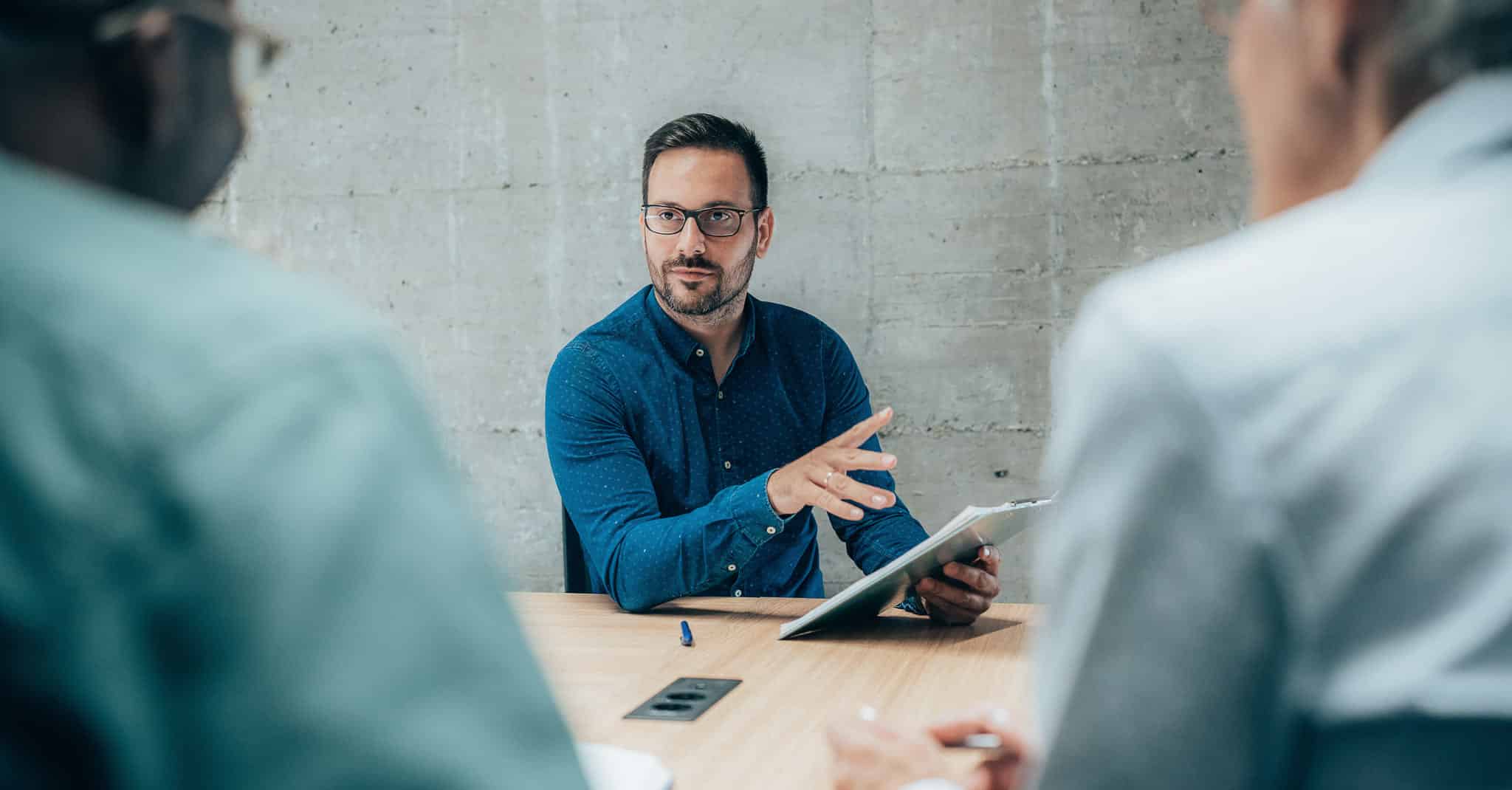 Tre menn sitter i et møte.