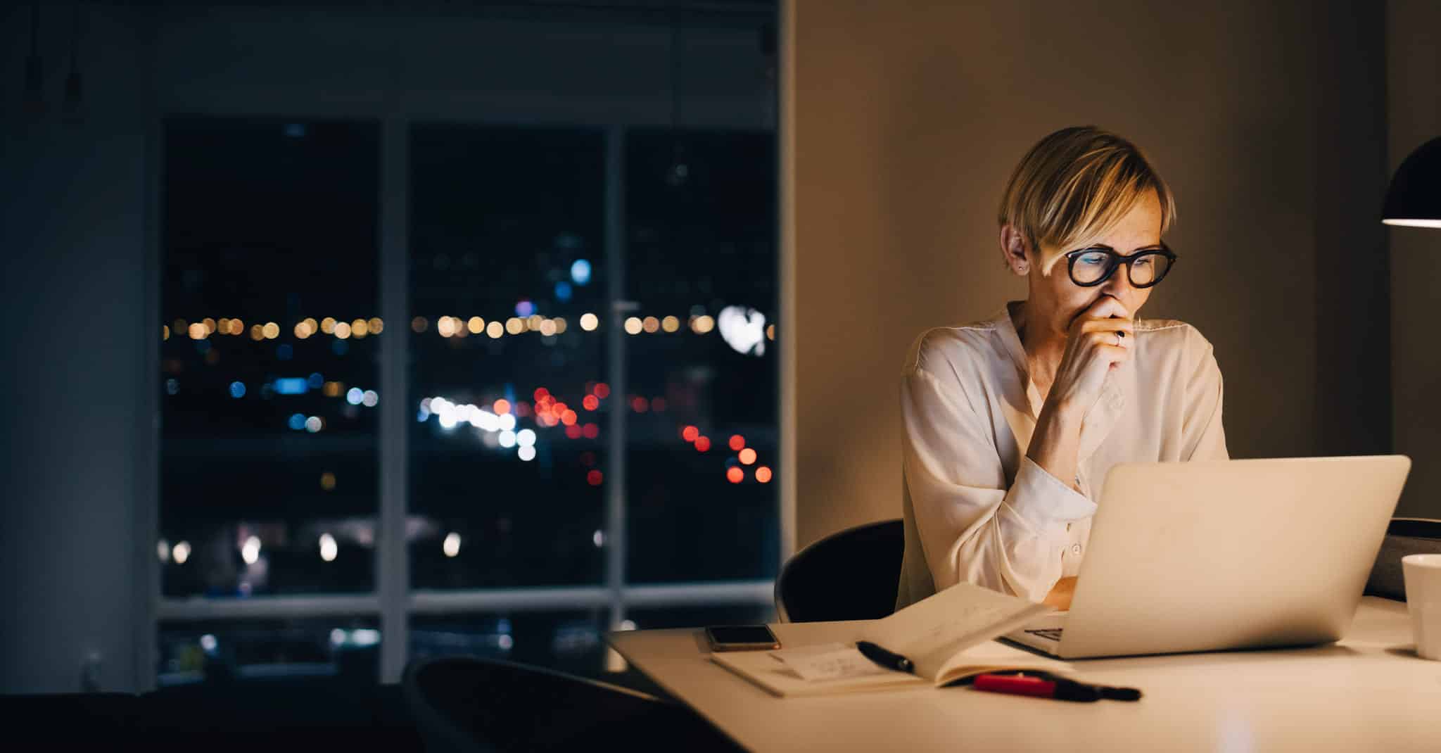 Kvinne sitter foran PCen på en sen kveld.