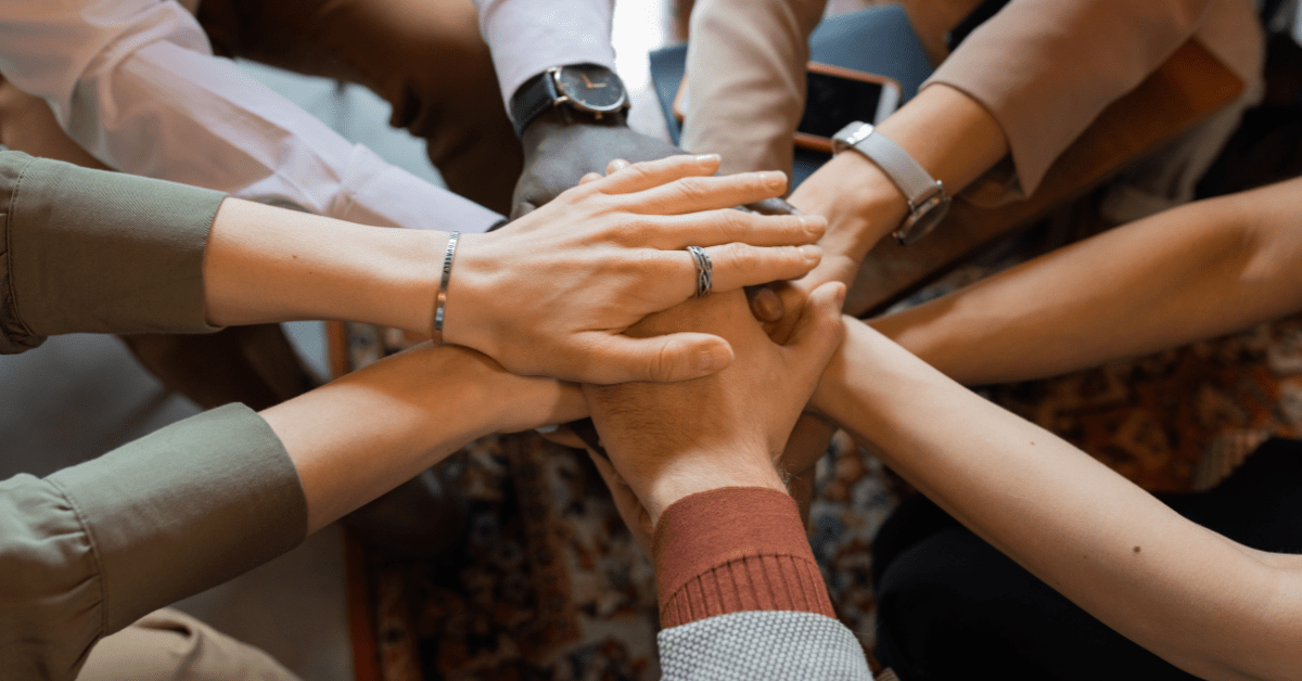 Mange hender som holder i hverandre.
