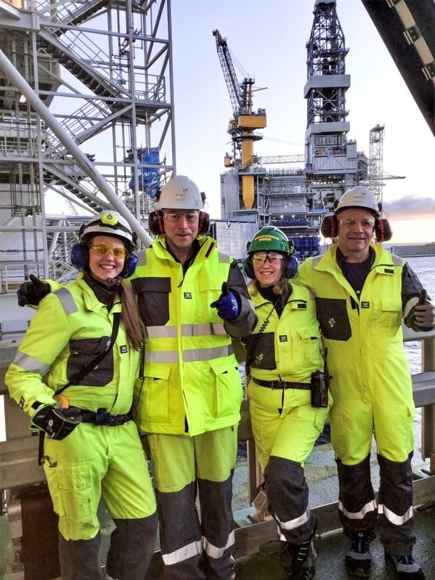 Fire medlemmer står kledd i sikkerhetstøy på plattform