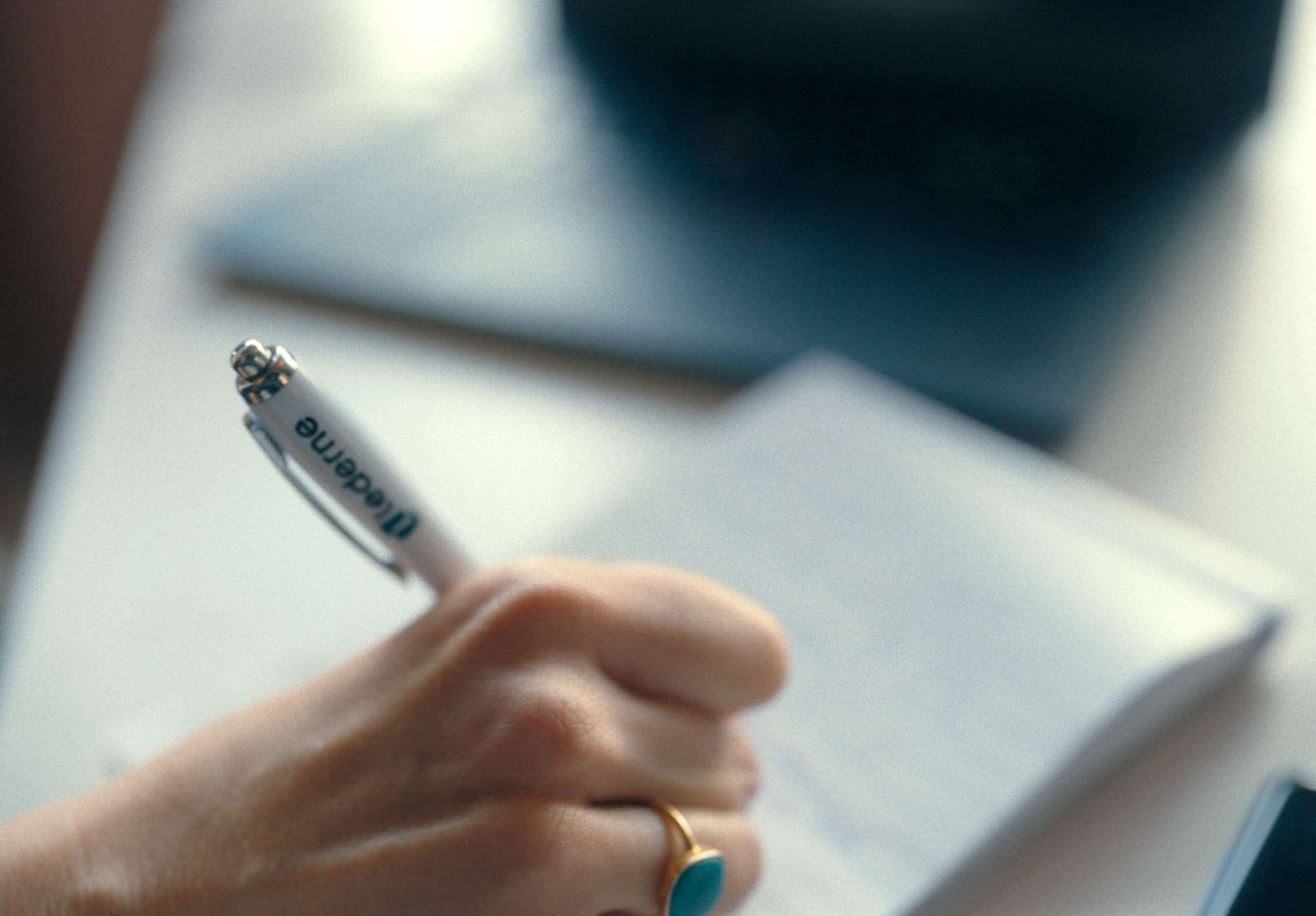 Hånd som skriver på blokk med Lederne-penn