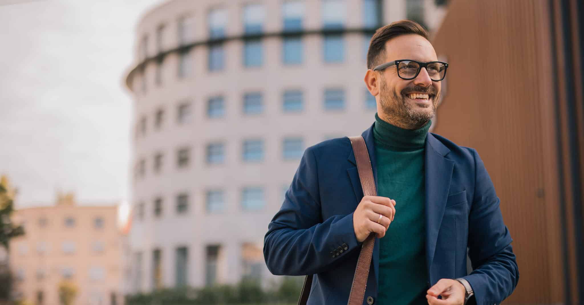 Man med briller og veske smiler