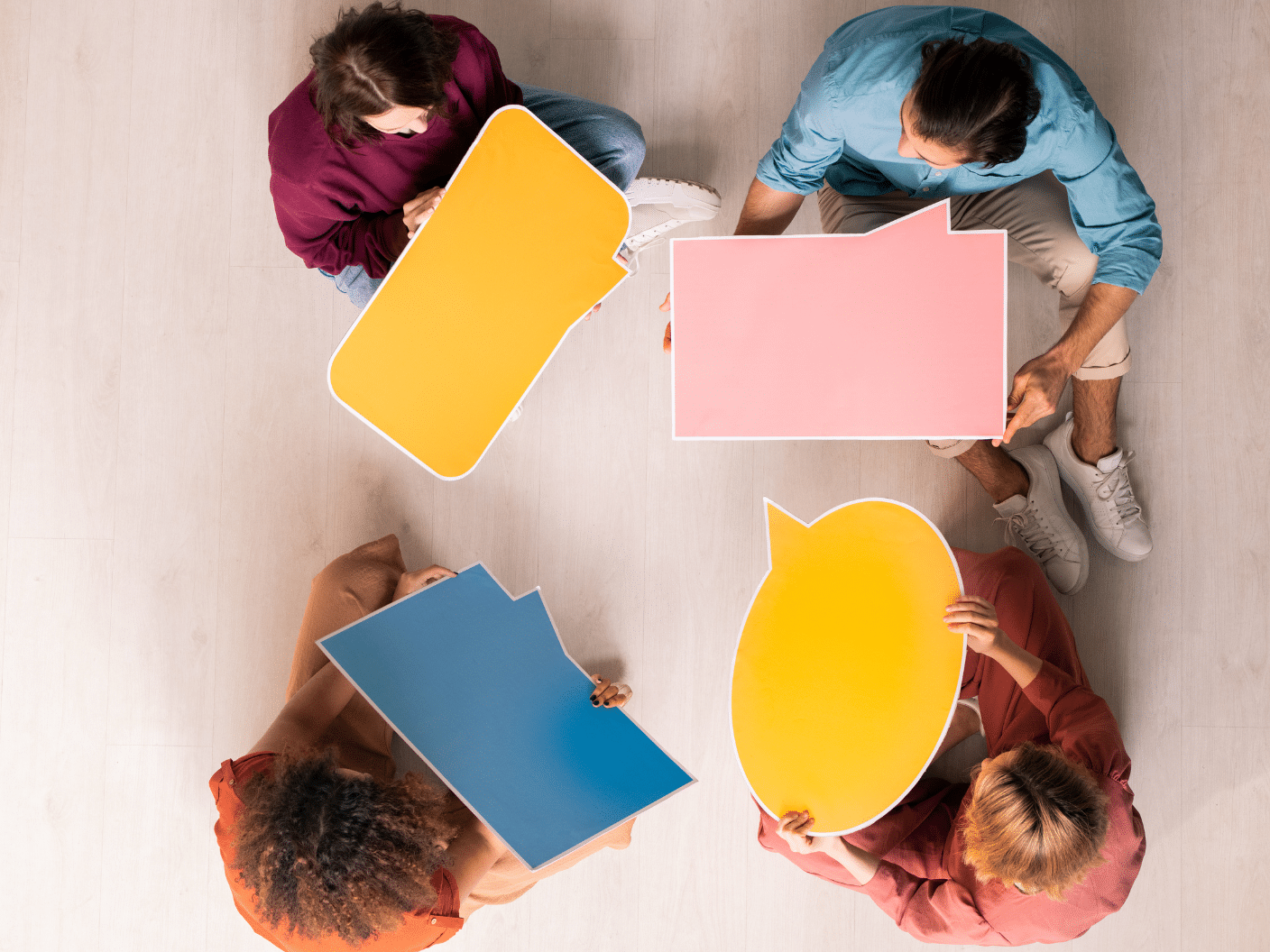 Fire mennesker som holder ulike snakkebobler sett ovenfra.