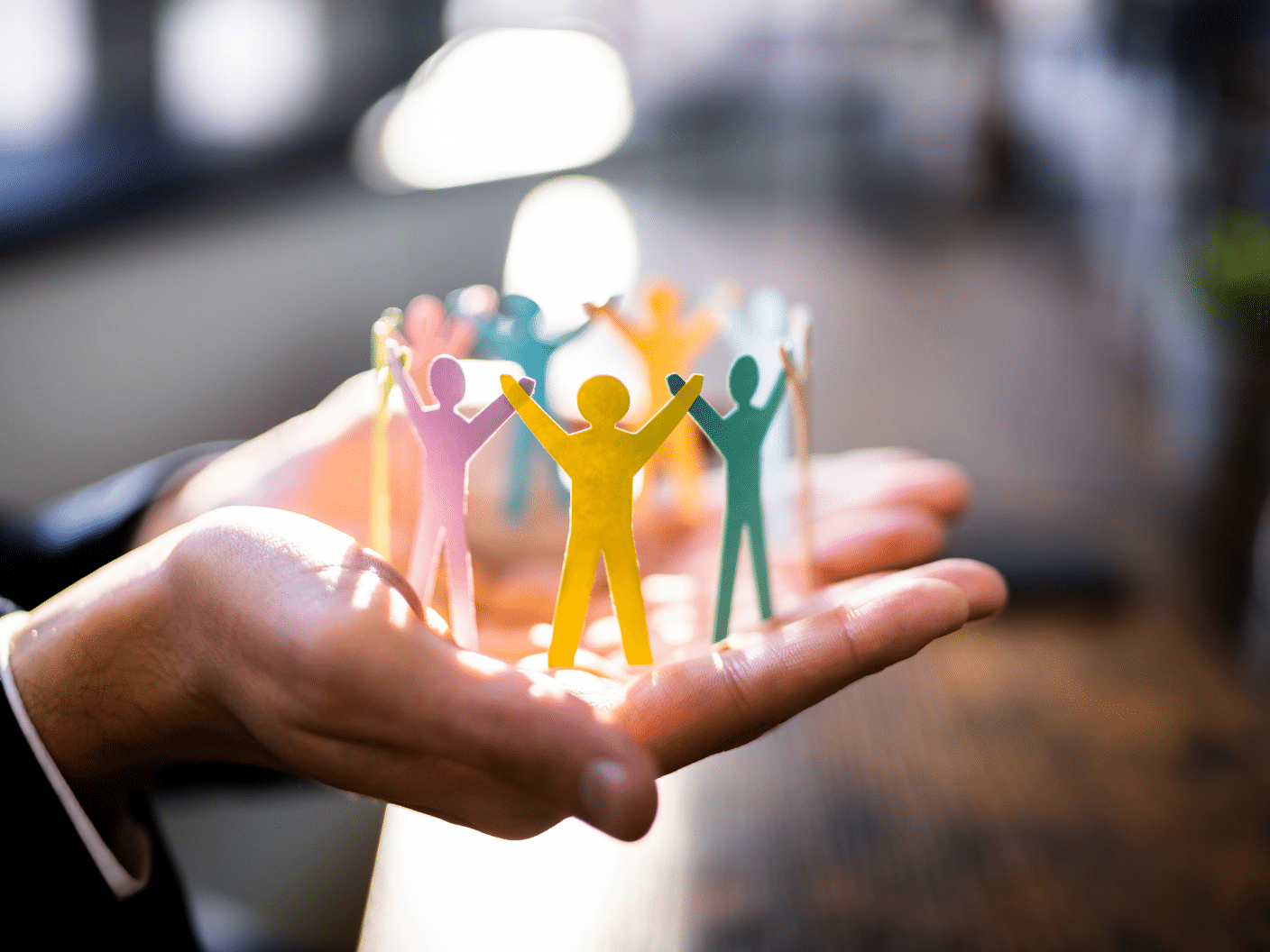 To hender med små papirmennesker i ulike farger