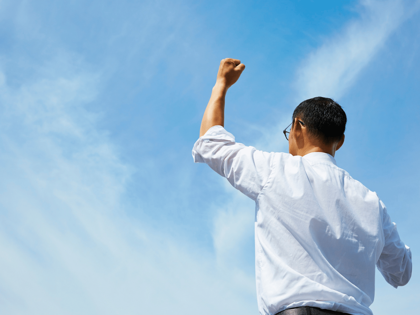 Mann under blå himmel som holder armen i været