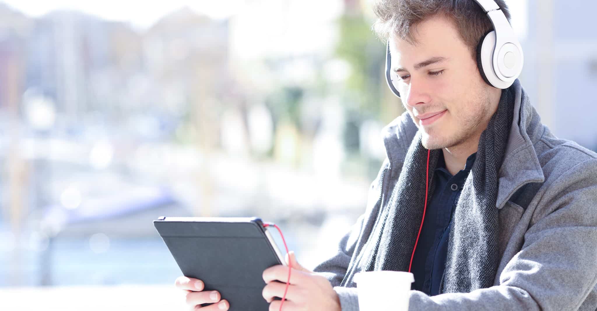 Man sitter med hodetelefoner og titter på en ipad