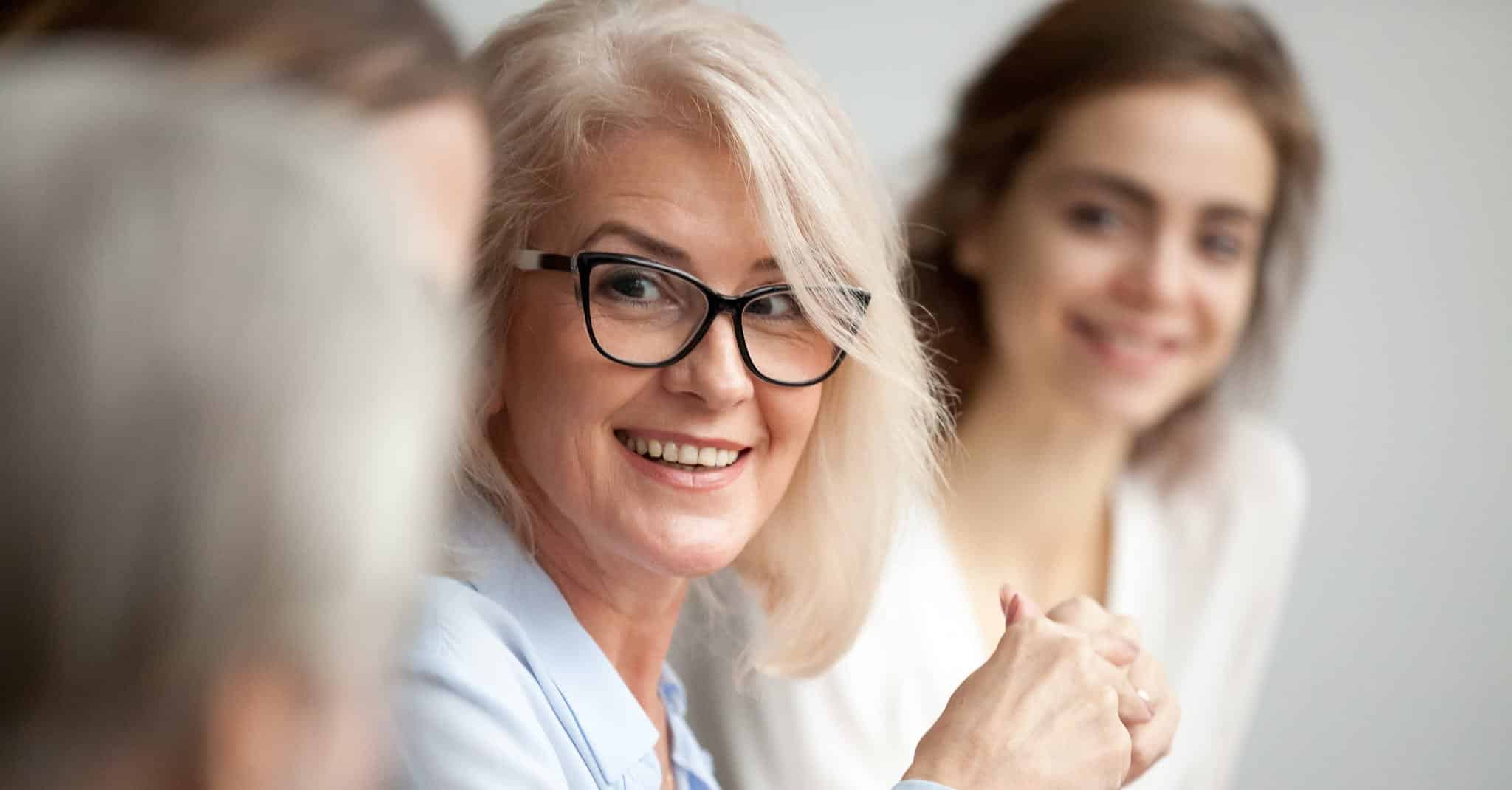 En dame smiler til en annen i et møte