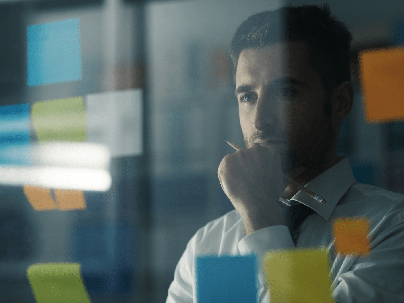 Tankefull mann som står foran vegg med post-it.