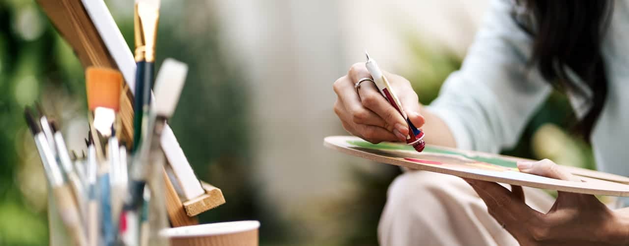 Malepensler og staffeli og en kvinne som maler