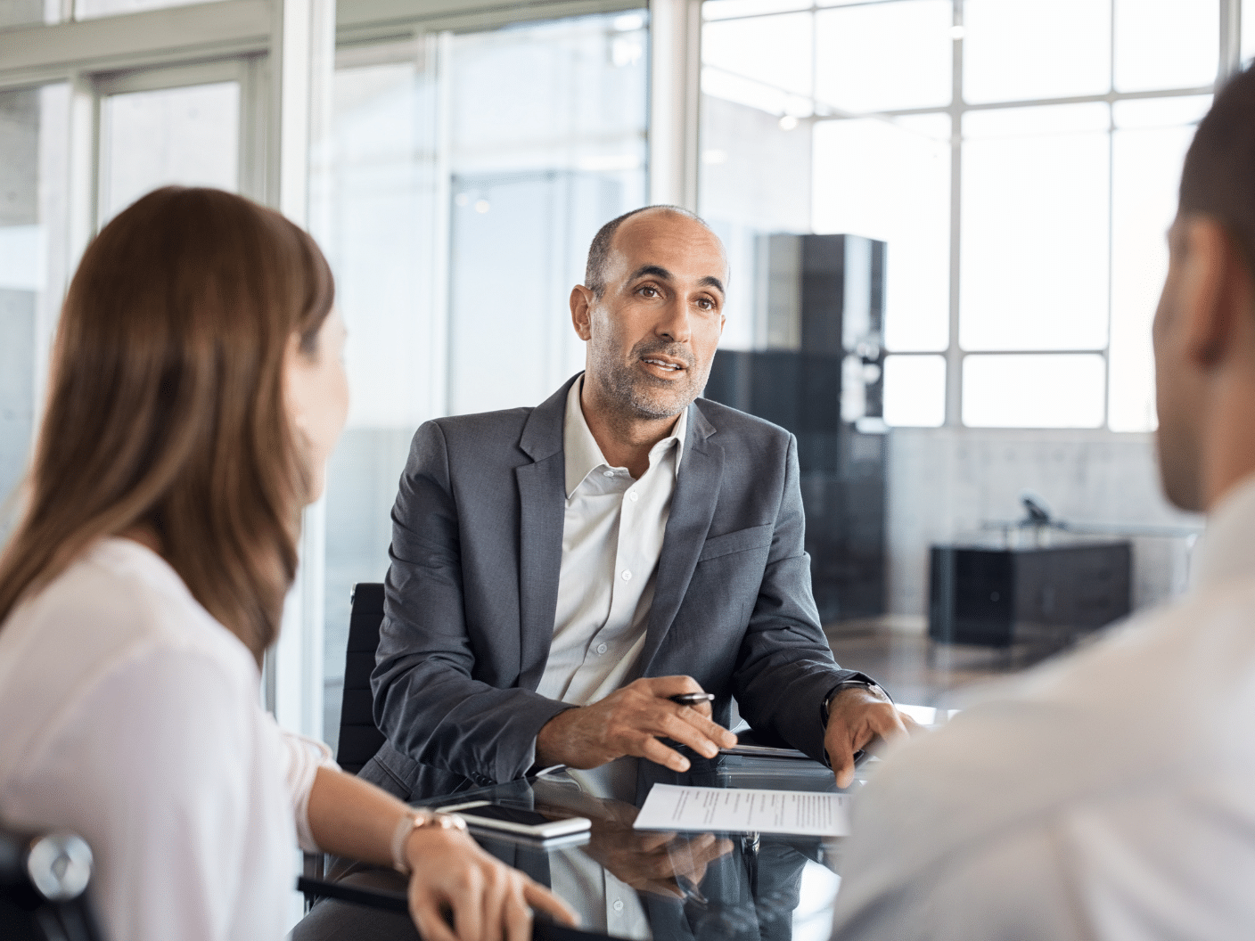 Mann i dress som snakker med to personer