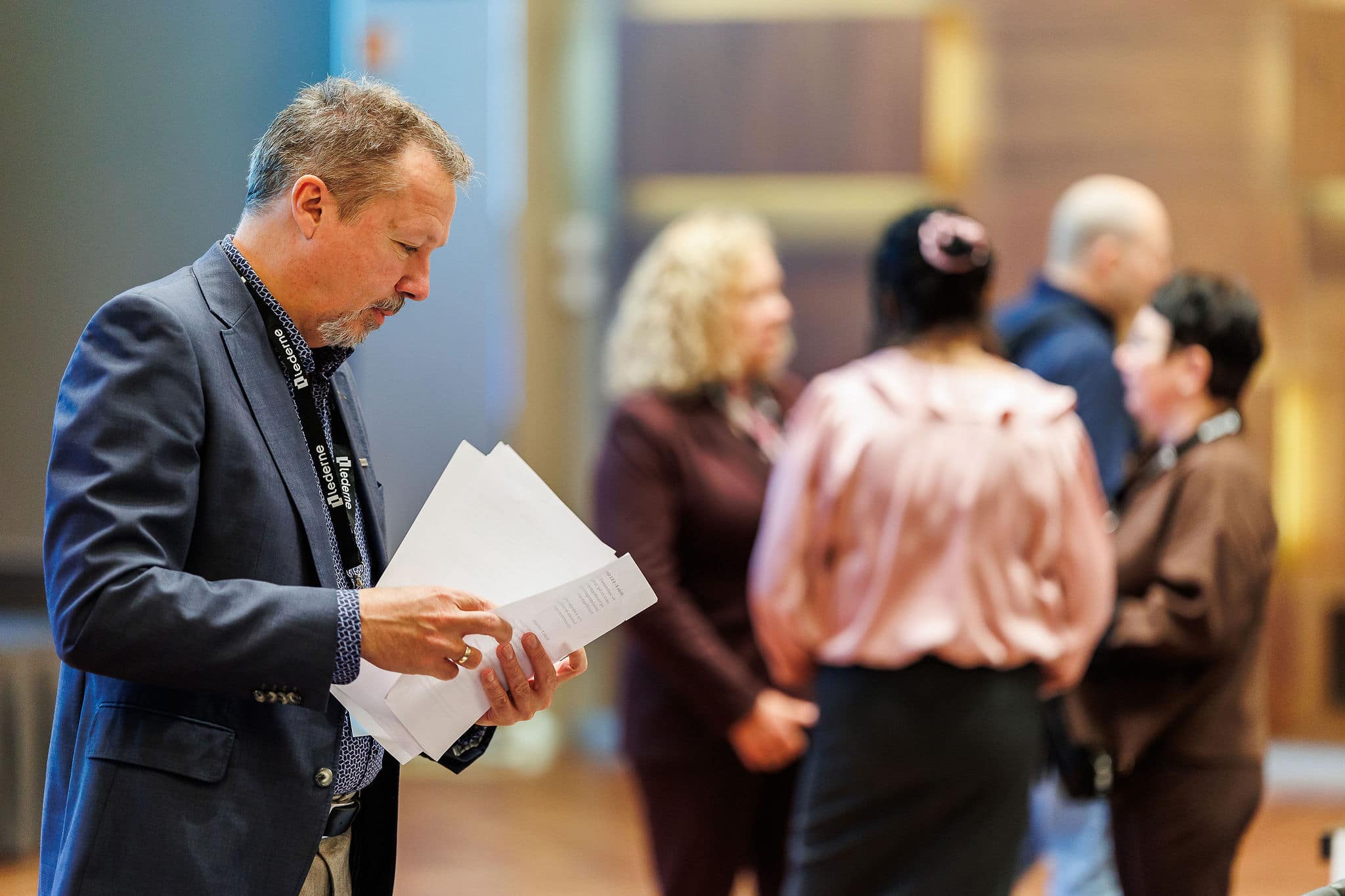 Mann som ser i papirer med fire mennesker i bakgrunnen