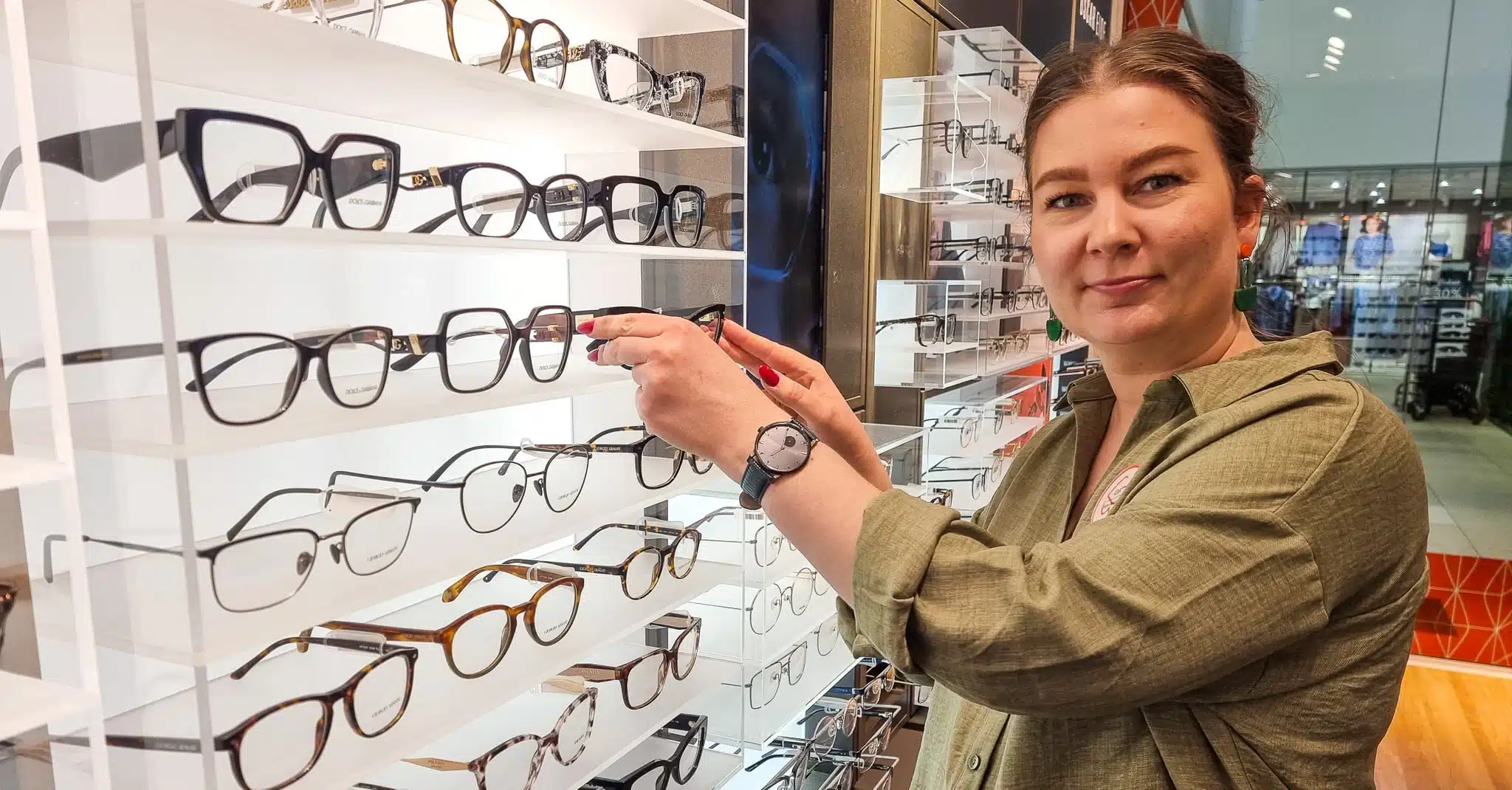 Ida Lutnæs Nordnes står ved en brillevegg på Synsam og ser inn i kamera