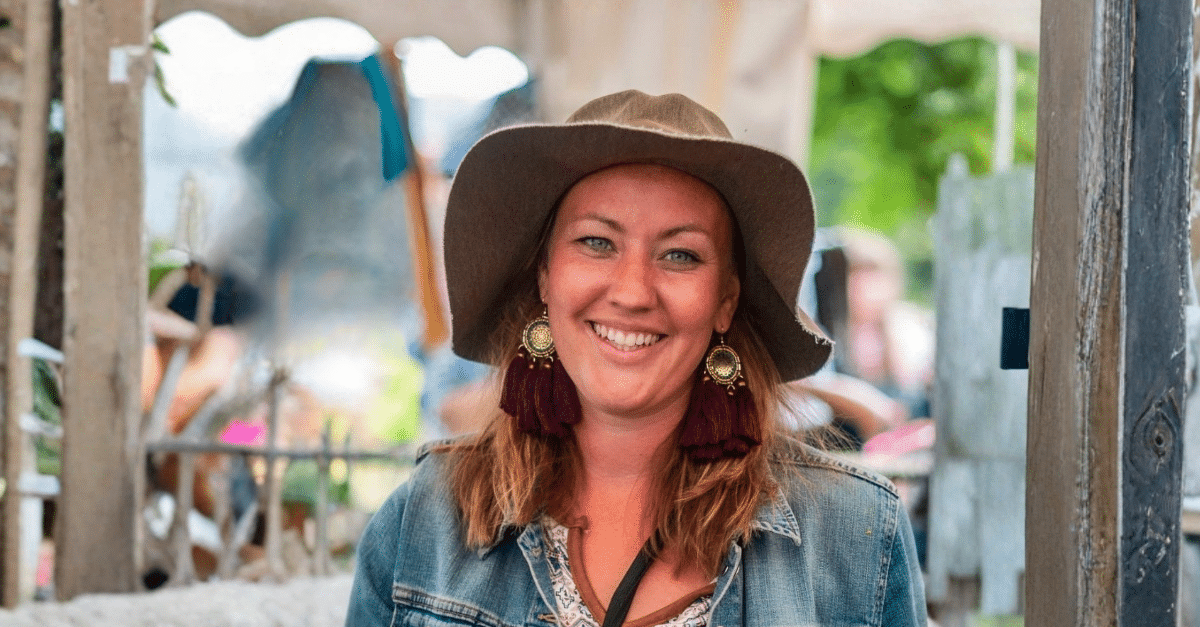 Martha Vatne smiler til kamera med hatt og store øredobber