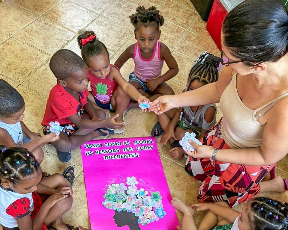En ansatt og barn ved mødrehjemmet Abrigo sitter i ring og leker.