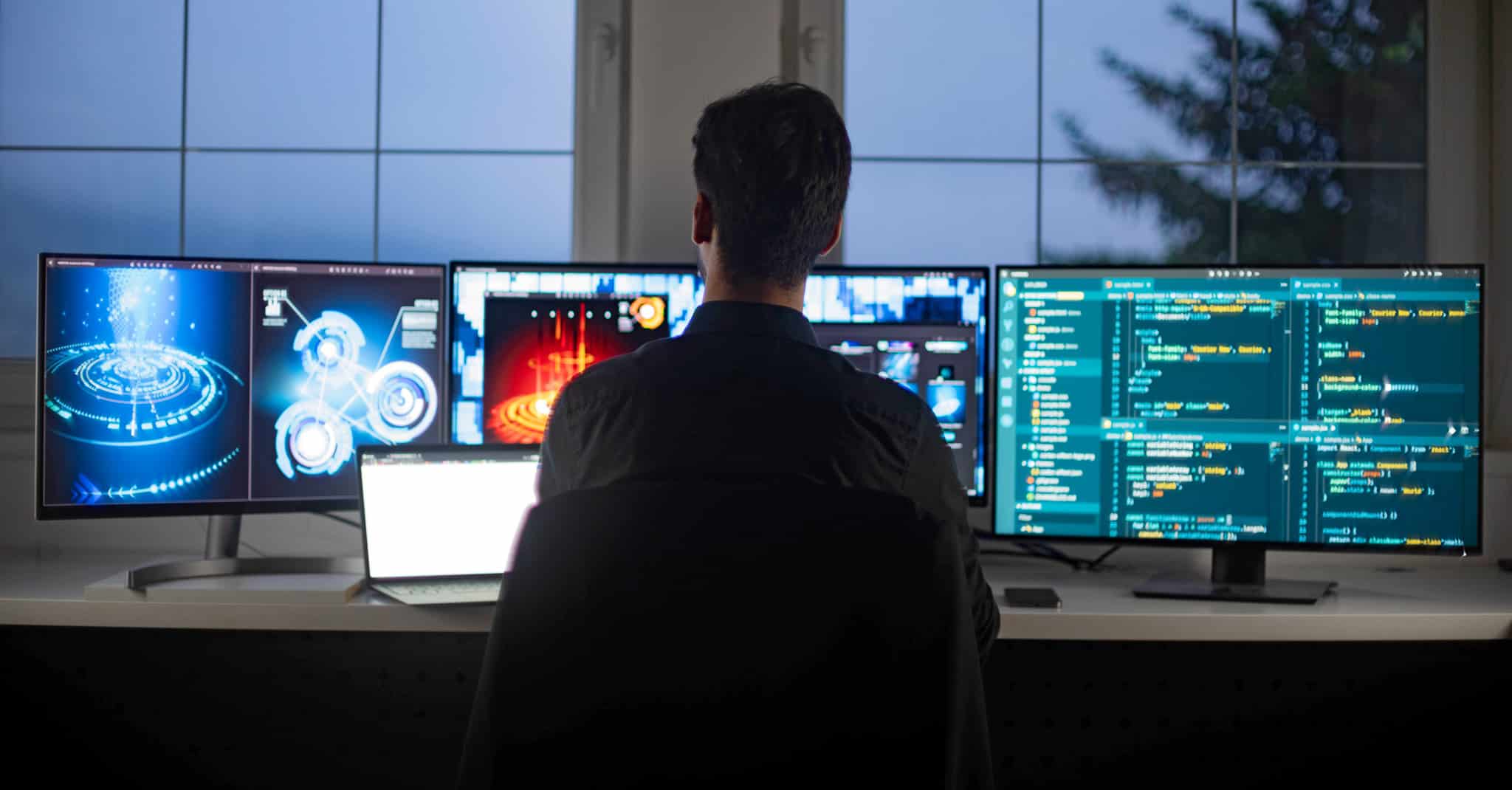 Mann sitter foran flere pc-skjermer.