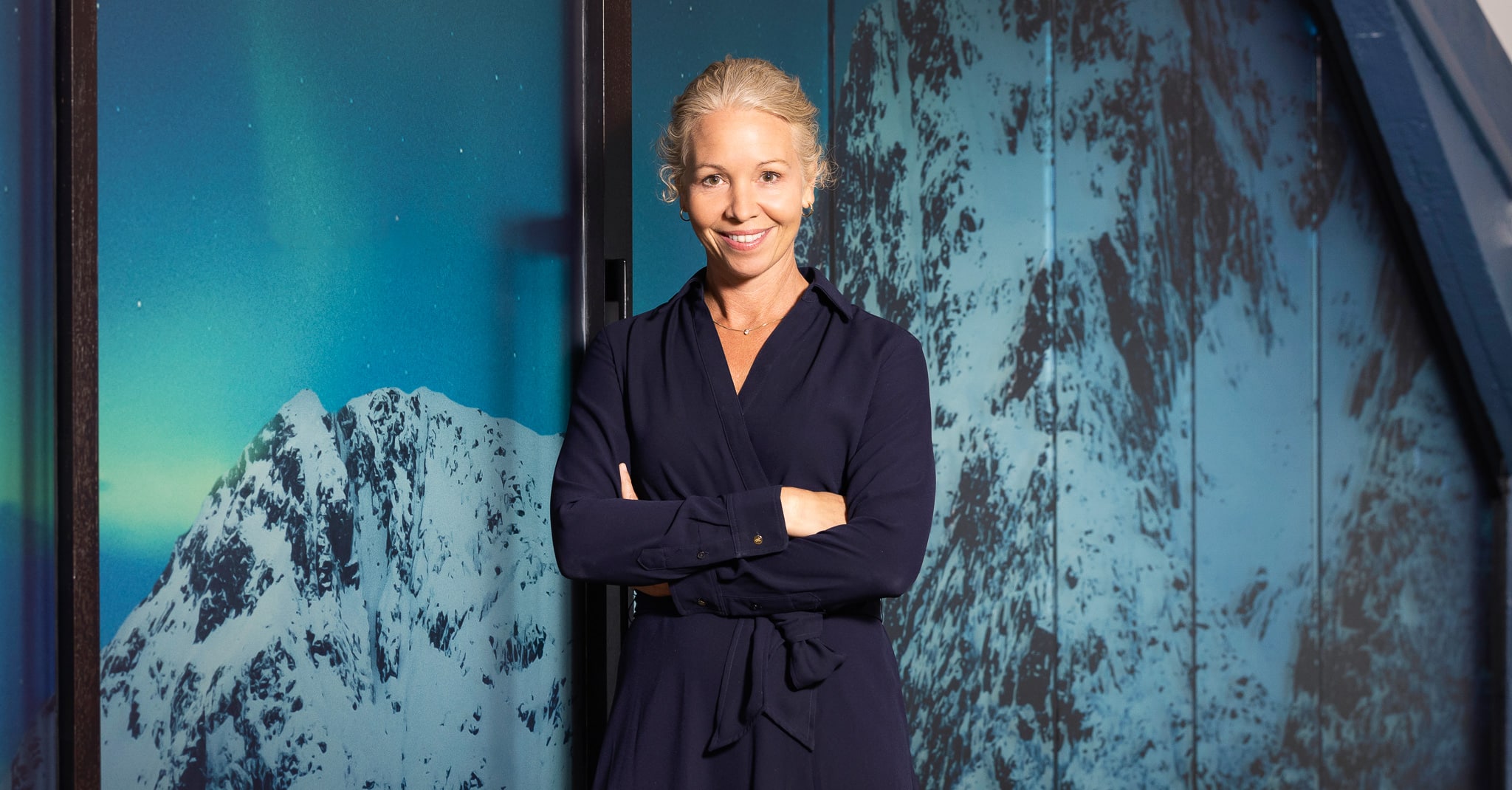 Hedda Felin står foran et bilde av snødekte fjell.