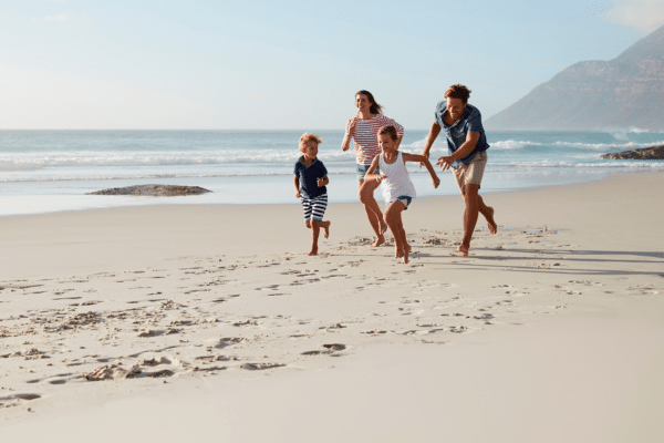 Glad familie på stranden - reiseforsikring